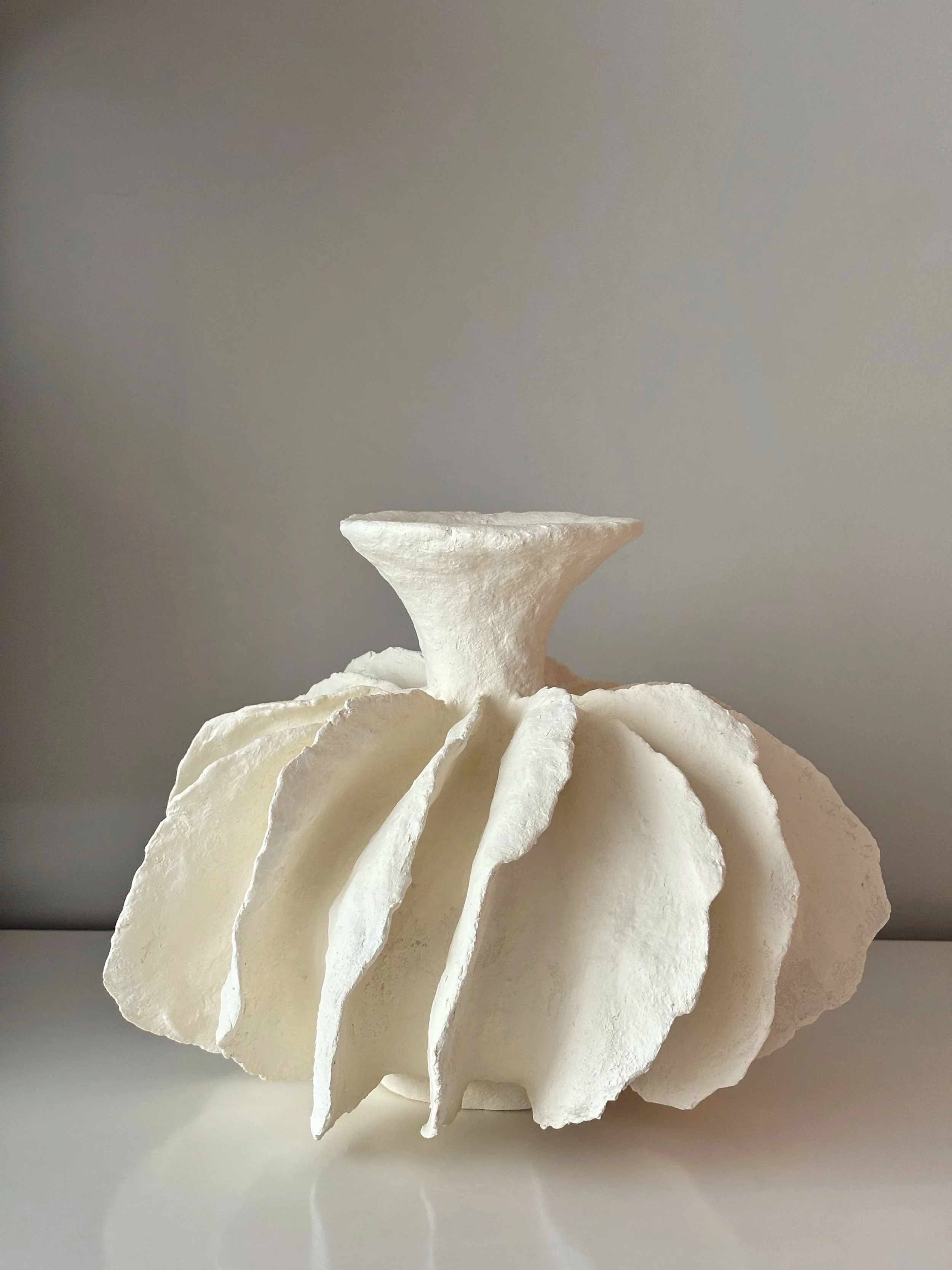 Three-quarter view of White Pleated Sculpture Vase N.12, white textured paper clay vase with organic irregular form, minimalist sculptural home decor