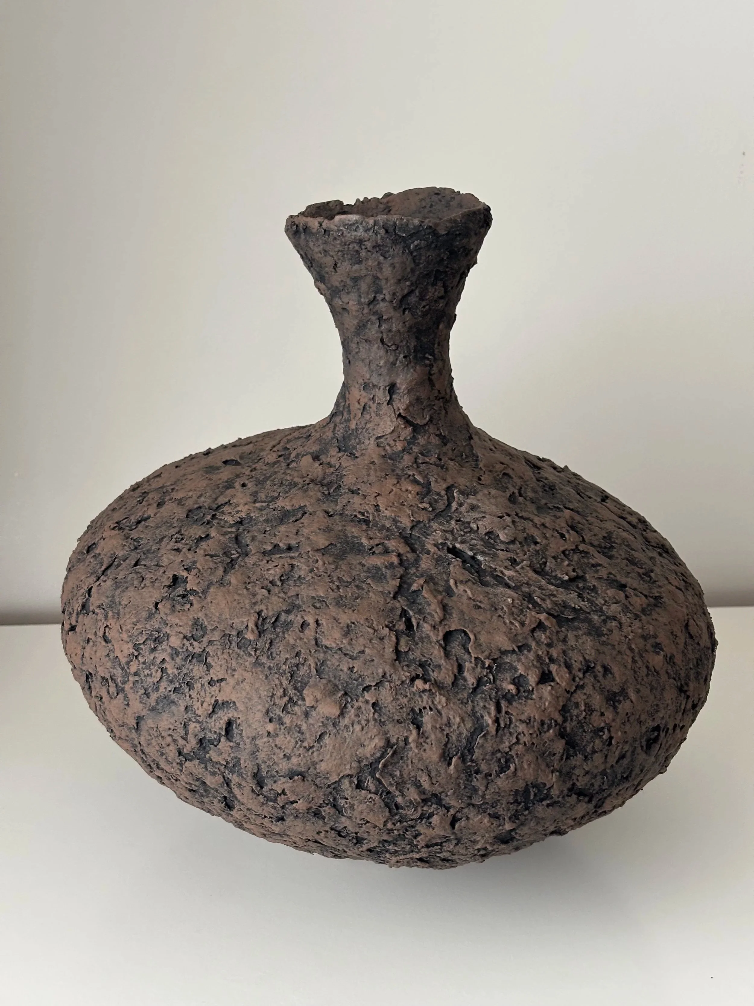 Three-quarter view of Tall Textured Vessel N.1, off-white textured paper clay vessel with organic irregular form, minimalist sculptural home decor