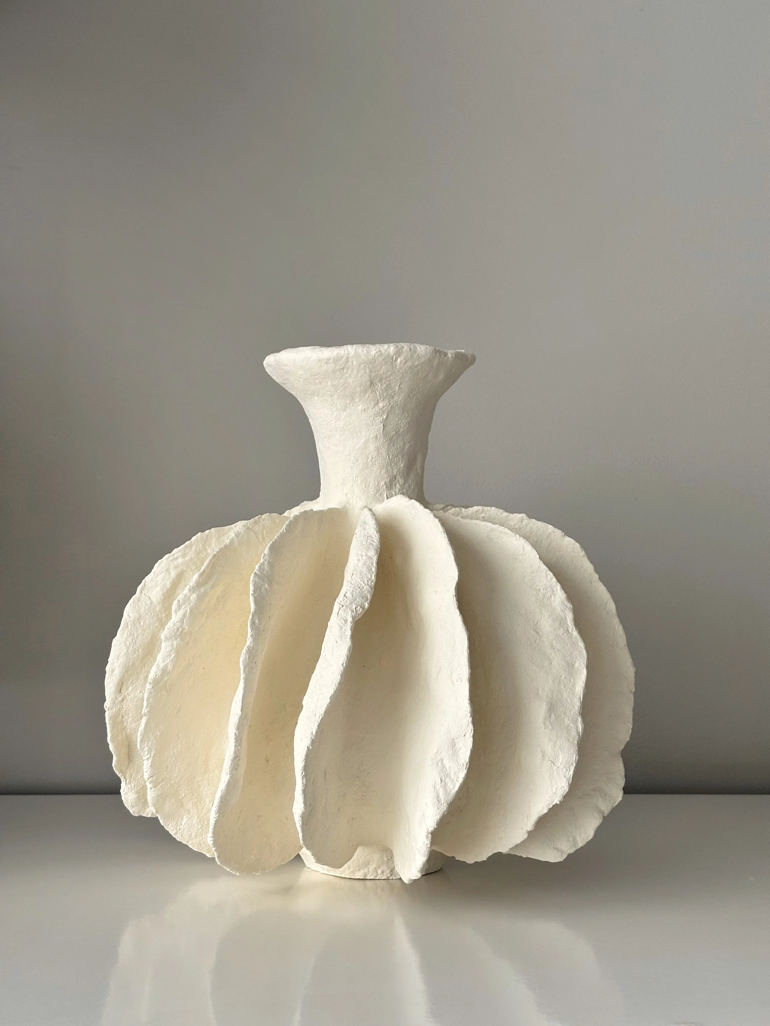 Three-quarter view of Pleated Sculptural Vase N.10, off-white textured paper clay vase with organic irregular form, minimalist sculptural home decor