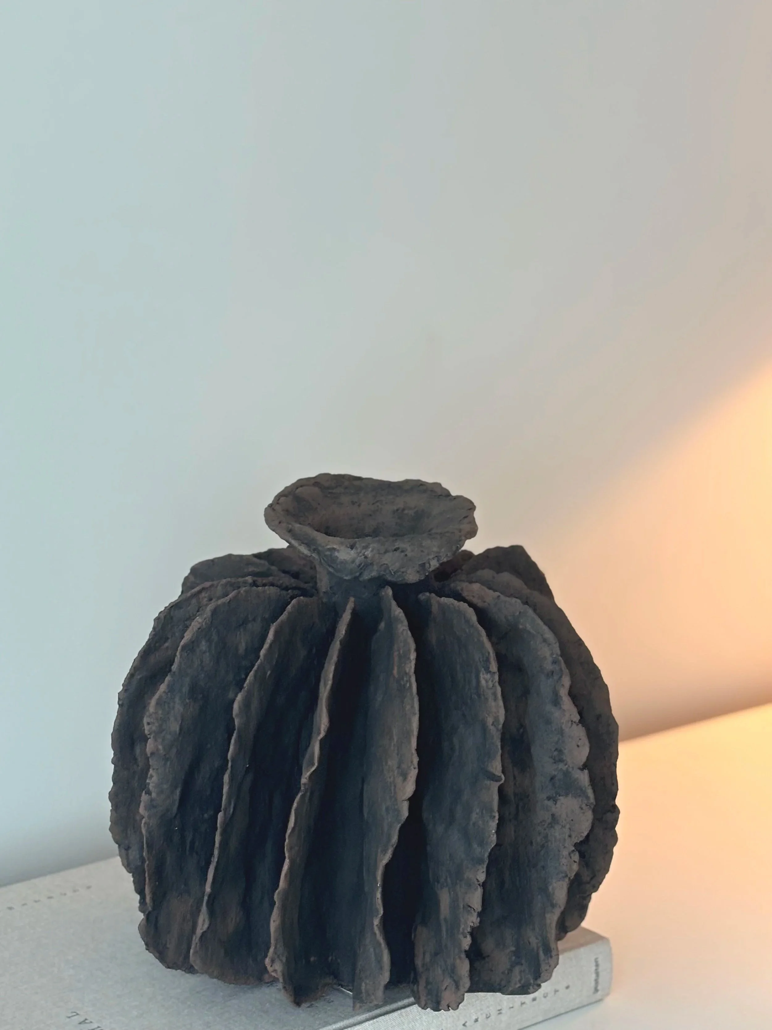 Textured Pleated Vessel N.8 shown in context, off-white textured paper clay vessel complementing a minimalist interior aesthetic