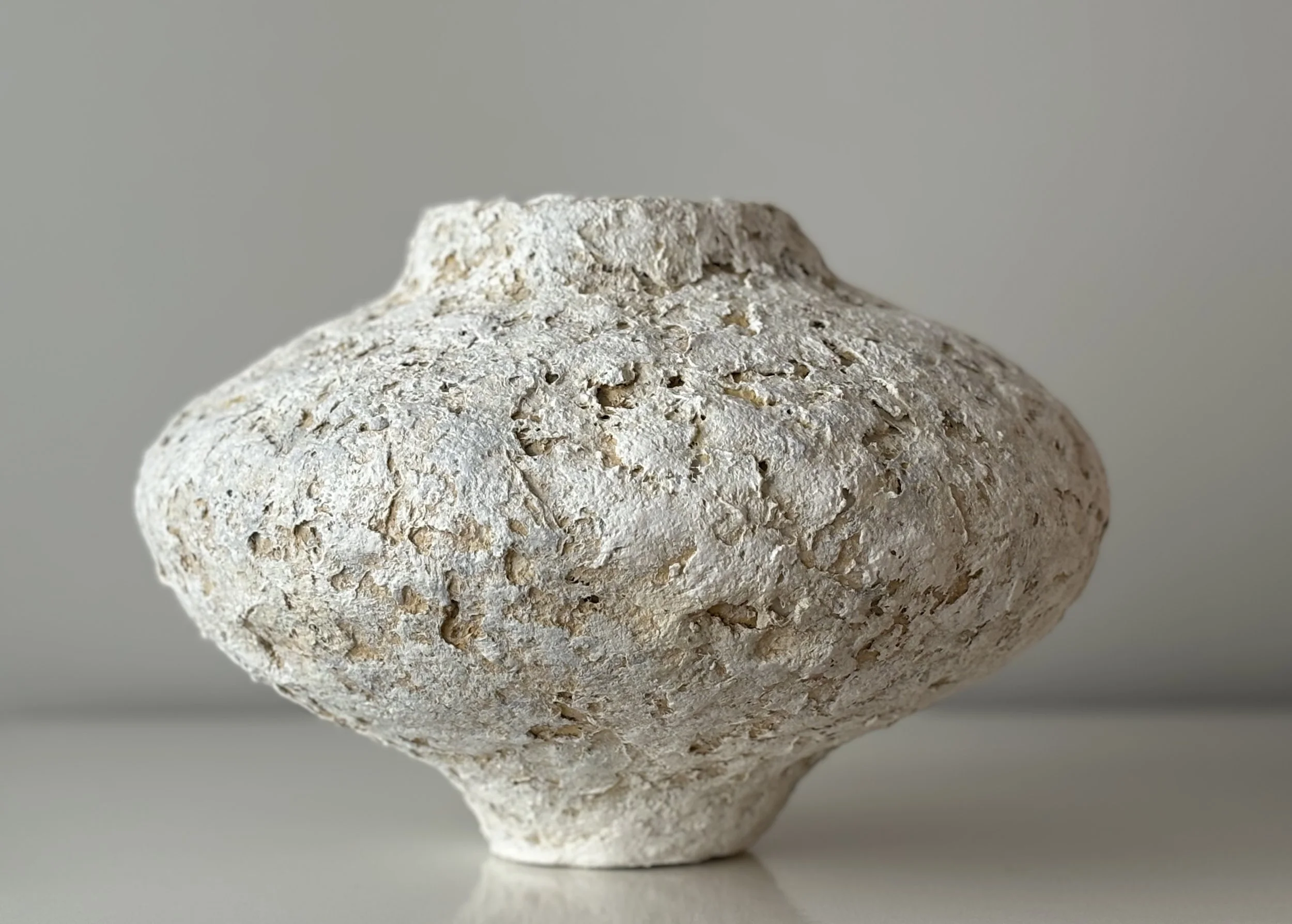 Three-quarter view of Contemporary Textured Vessel N.75, off-white textured paper clay vessel with organic irregular form, minimalist sculptural home decor