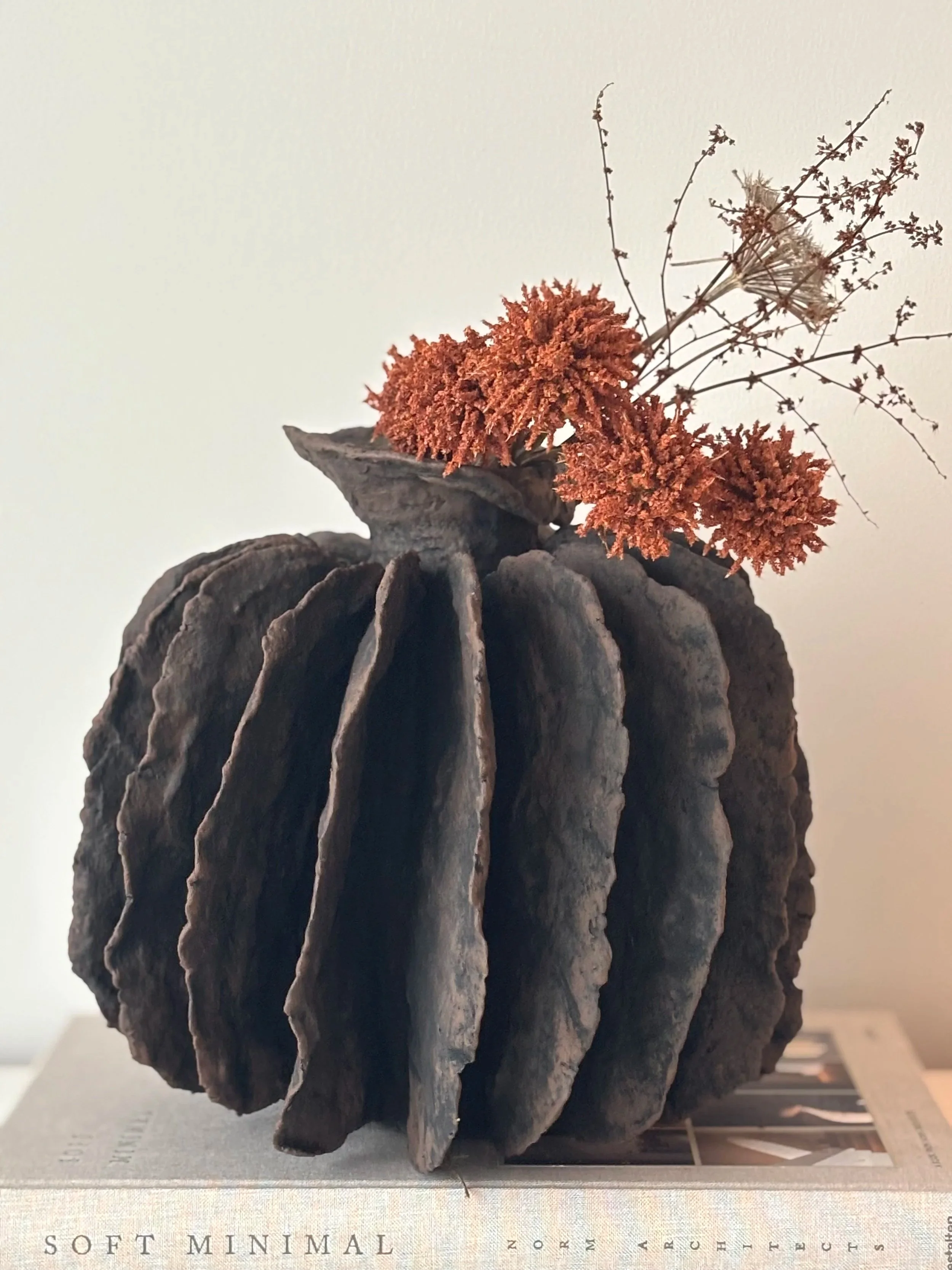 Textured Pleated Vessel N.8 displayed in a styled setting, off-white Wabi-Sabi inspired paper clay vessel as minimalist sculptural home decor