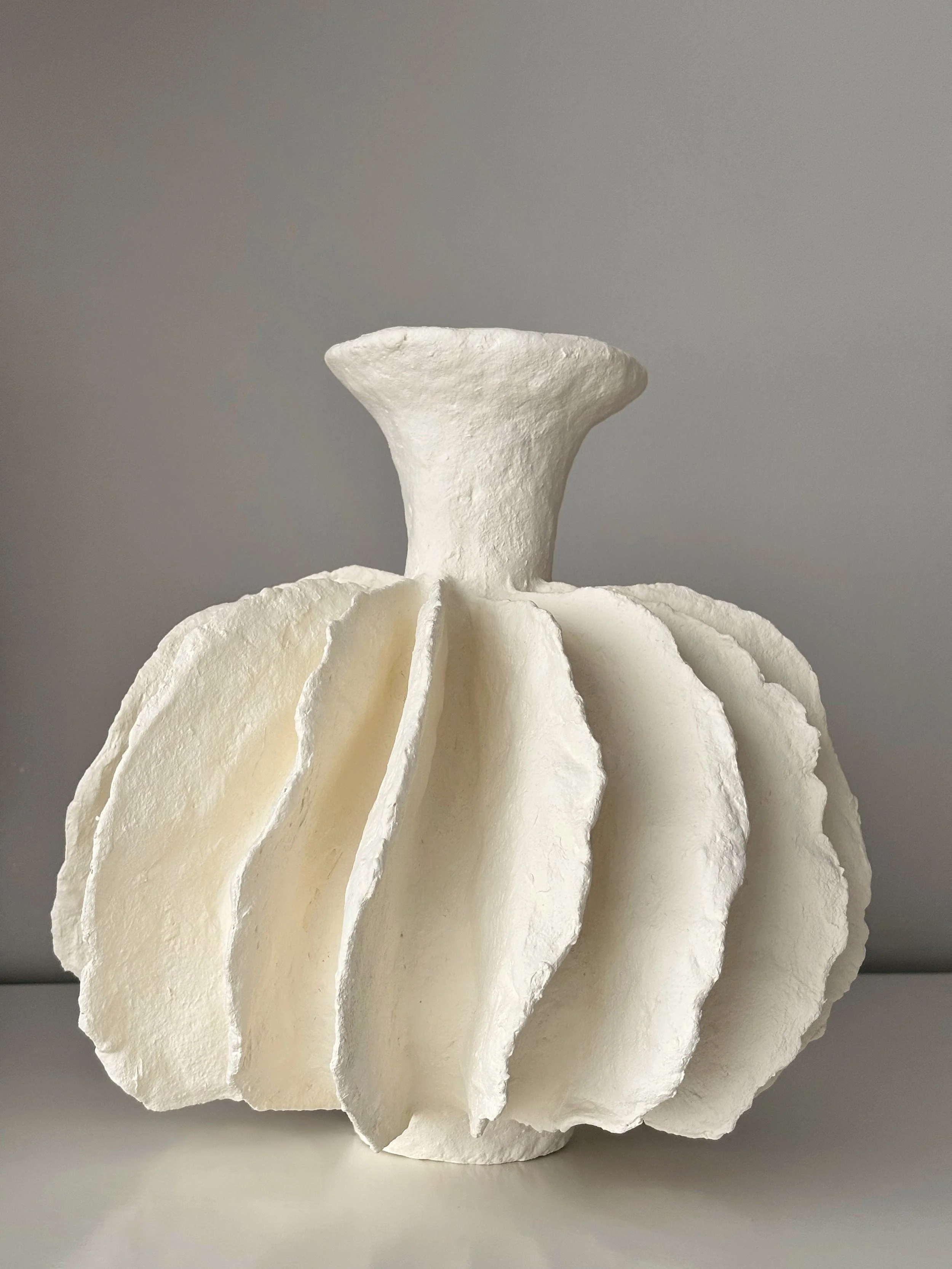 Rear view of Pleated Sculptural Vase N.10 in off-white paper clay, showing organic asymmetry from behind, from Papier Atelier London