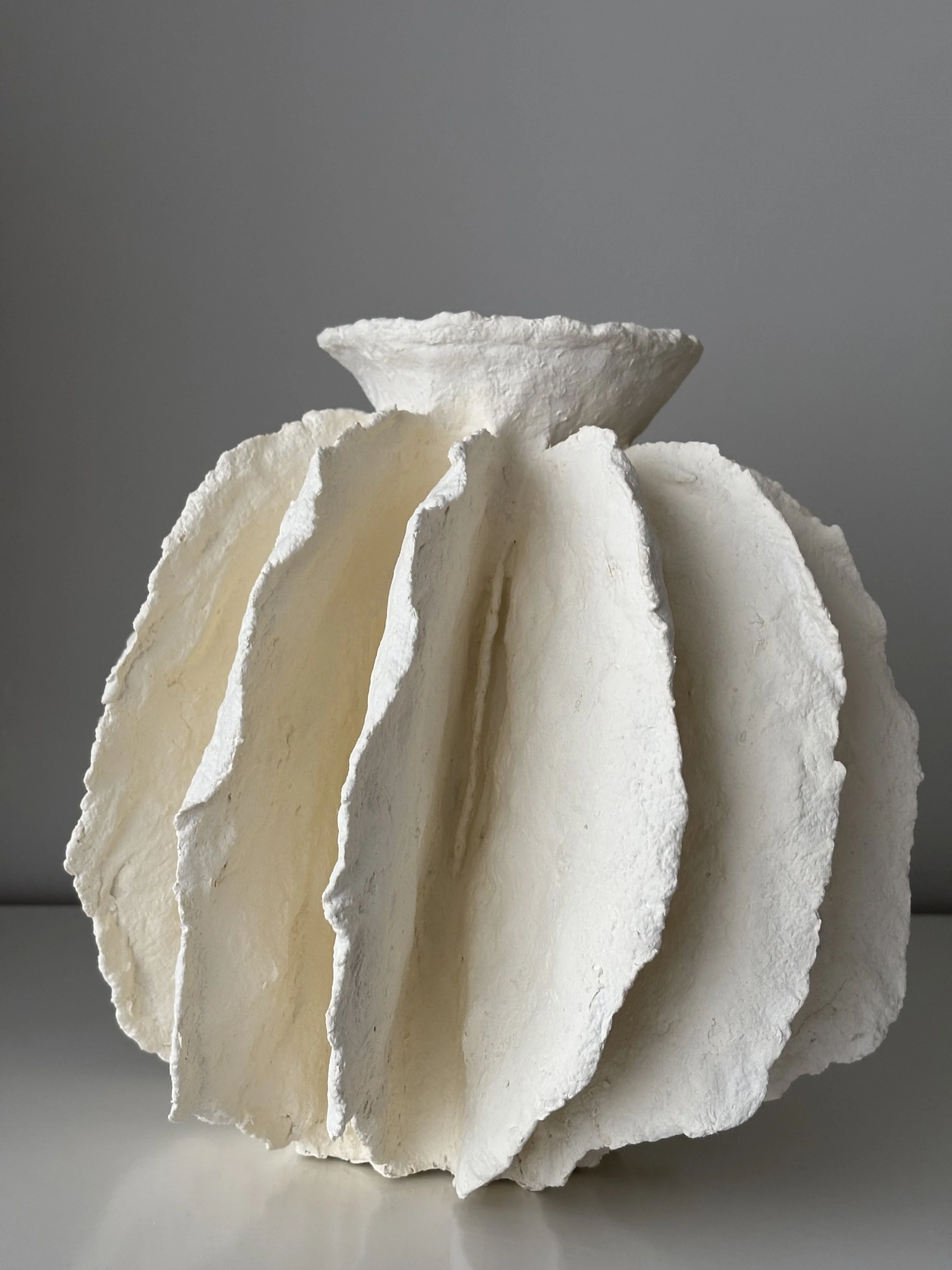 White Sculptural Pleated Vessel N.43 from an angled perspective, white handcrafted paper clay vessel with irregular organic edges, handmade in London