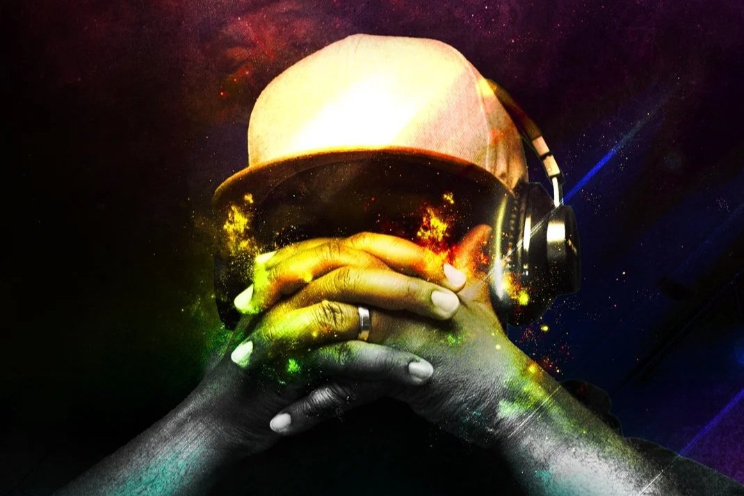A person wearing a pink cap and black headphones rests their eyes with hands, surrounded by a colorful, cosmic overlay.