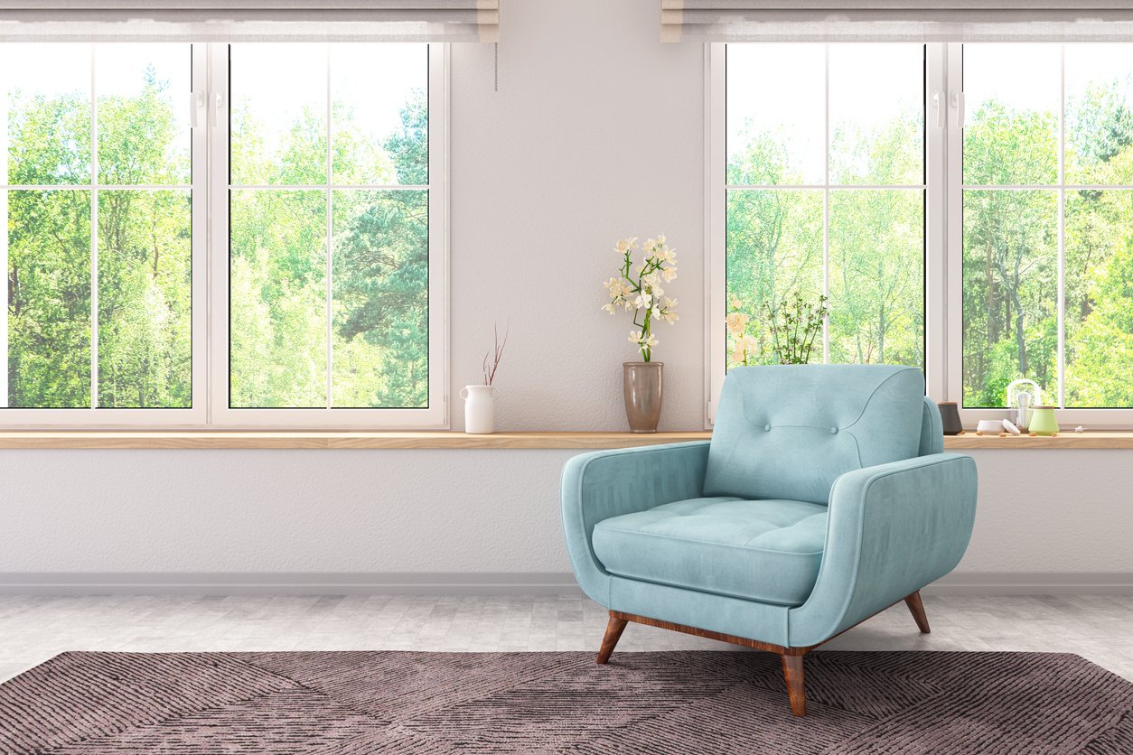 Comfortable blue armchair in a bright, private room with large windows and greenery outside — a calm, discreet space