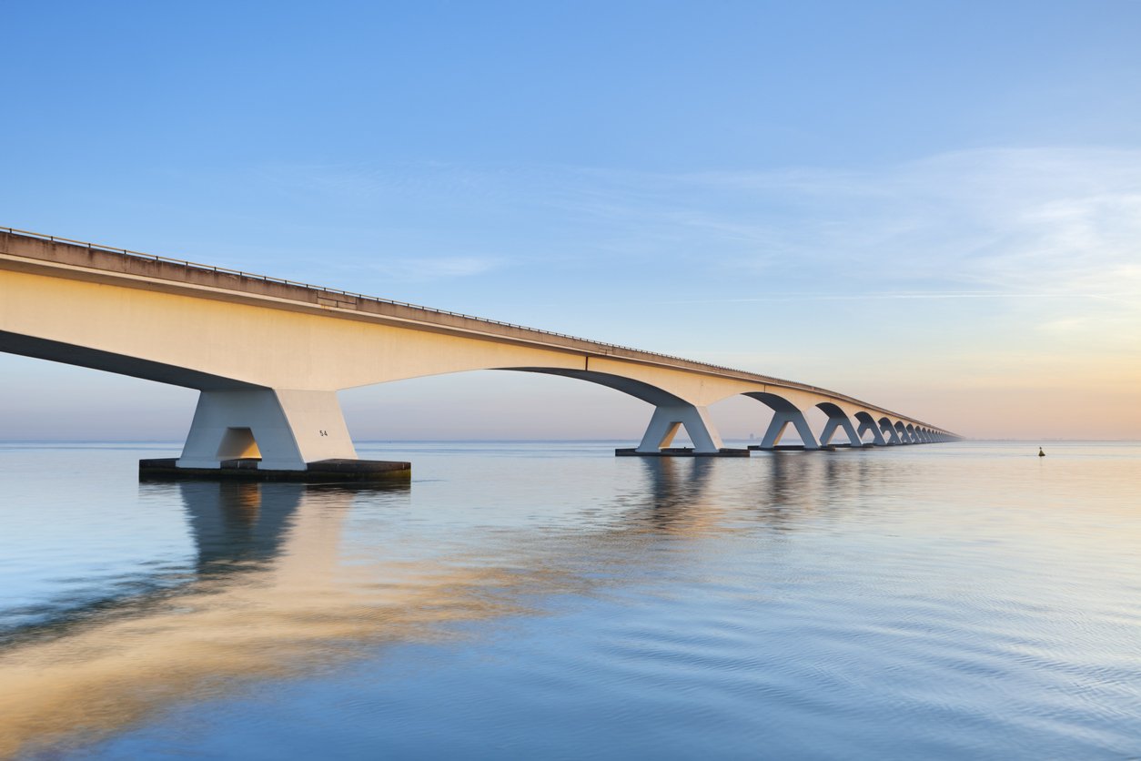 Long bridge stretching across calm water at sunset — building the bridge between today and tomorrow you