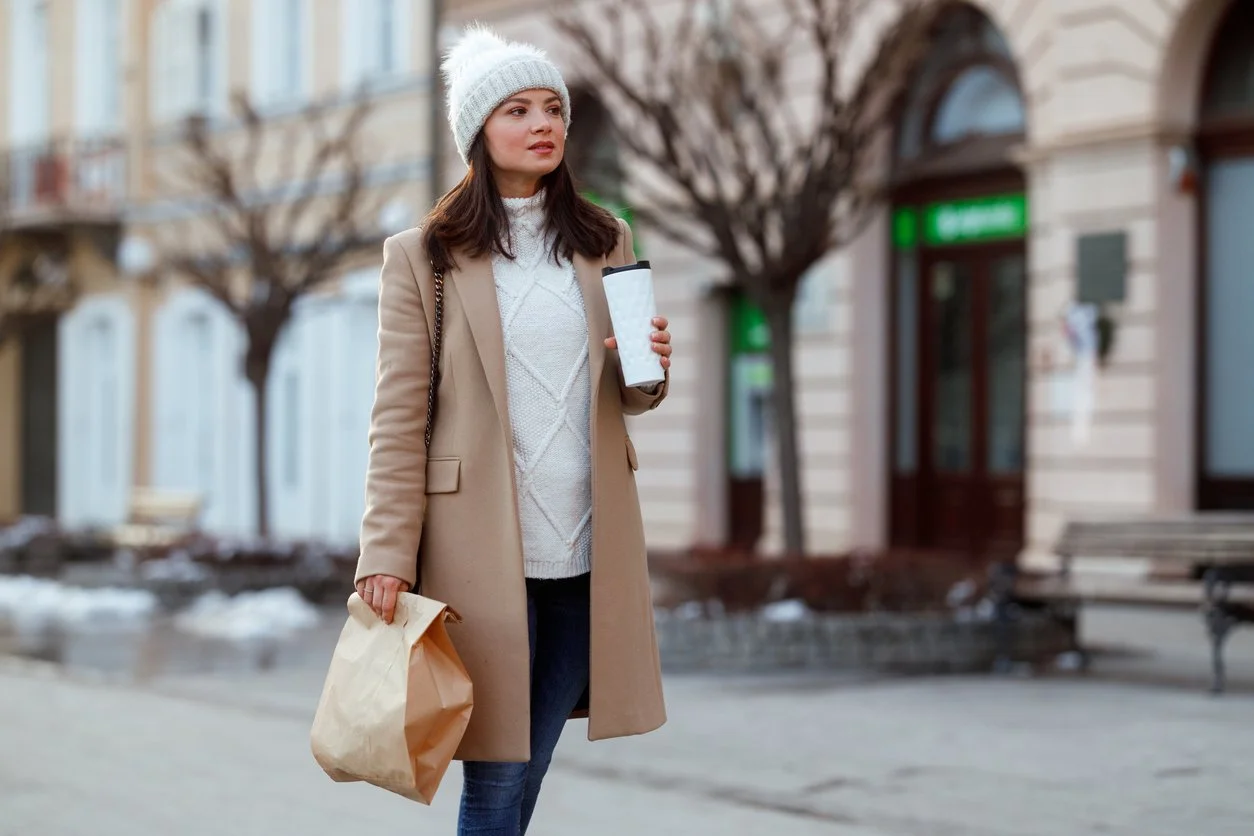 Young woman walking to work with coffee and bag, career-focused and in motion