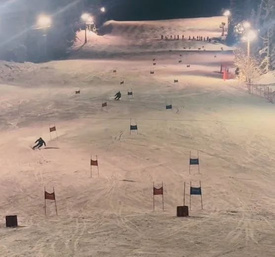 World Cup Friday night races under the lights  with skiers navigating through a giant slalom course marked by red and blue gates.