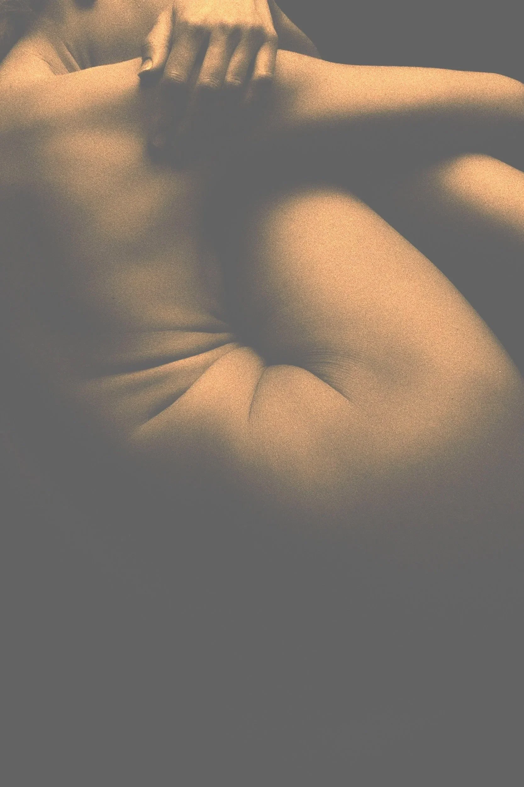 A close-up of a person lying down with hands resting on their shoulder, wearing a light-colored top.