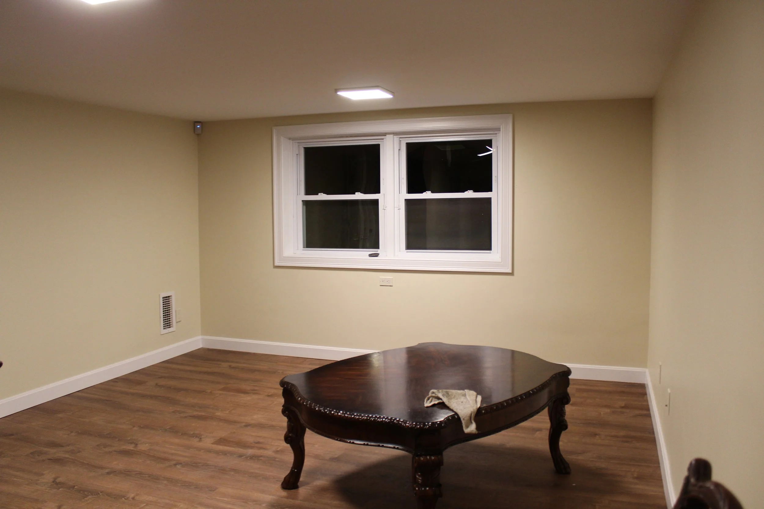 Empty room with beige walls, a window, and a wooden table with a cloth on top.