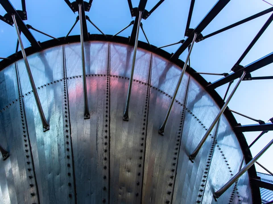 Close-up of the underside of a piece of grain equipment with metal supports and a clear blue sky.