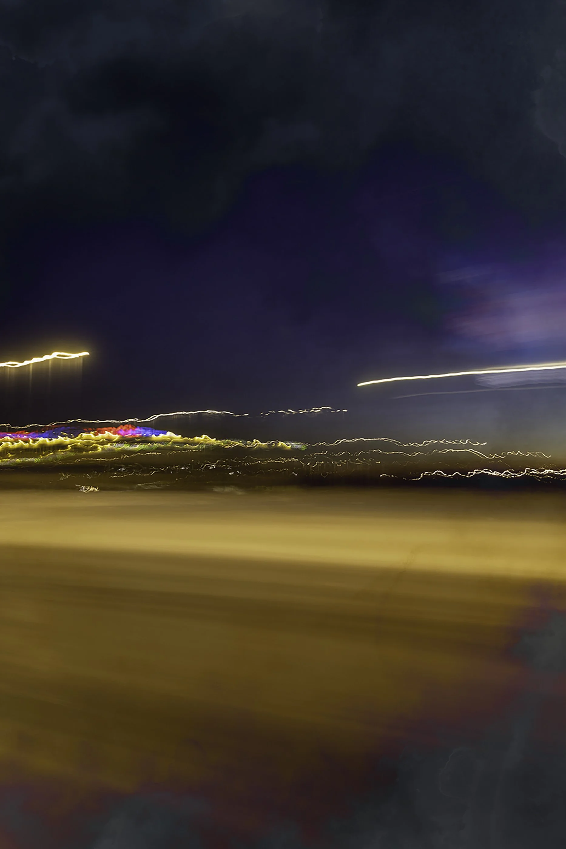 Blurred night scene of a cityscape with streaks of light from moving vehicles and illuminated buildings, viewed from a moving vehicle.