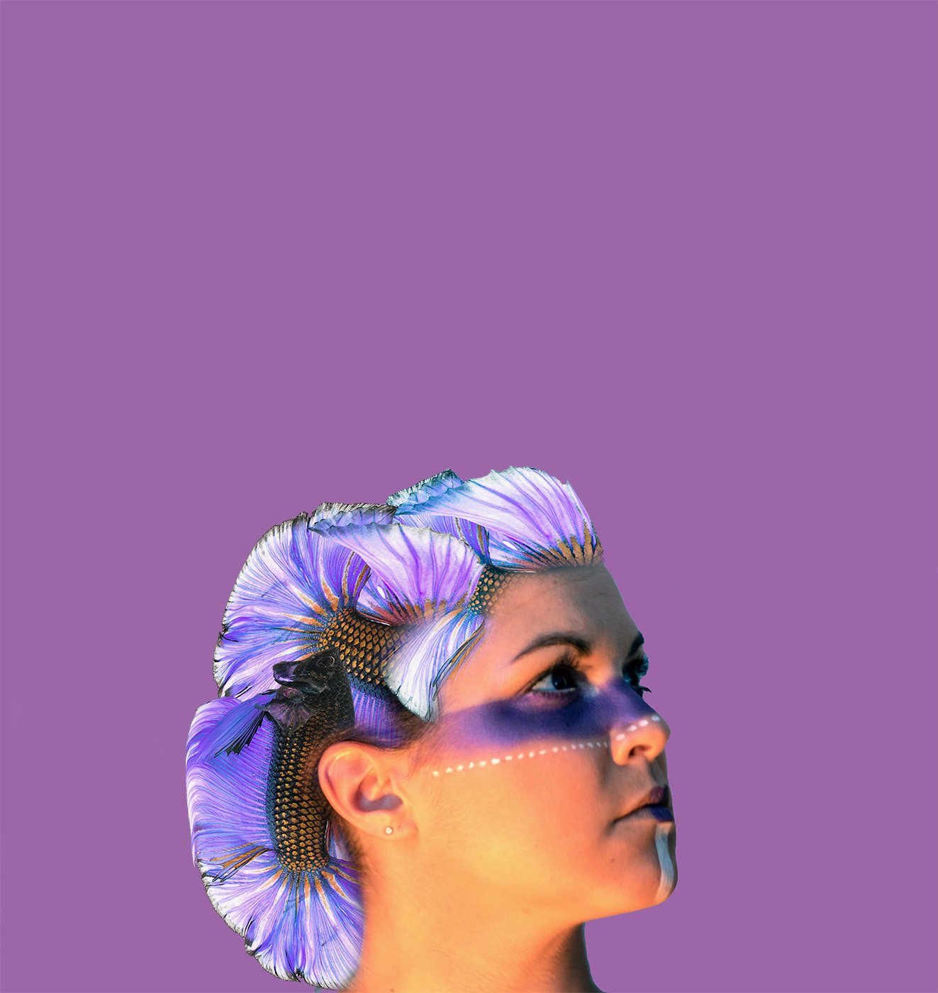 A woman with face paint and a headpiece resembling a large, colorful fish with purple, blue, and orange hues, set against a purple background.