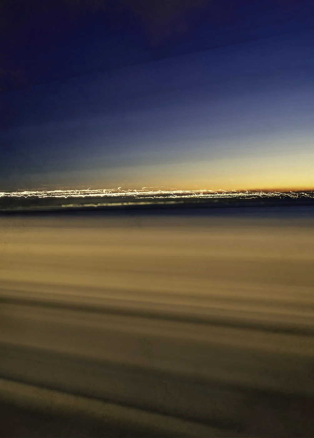 Blurred image of a sunset and a distant cityscape, taken from a moving vehicle.