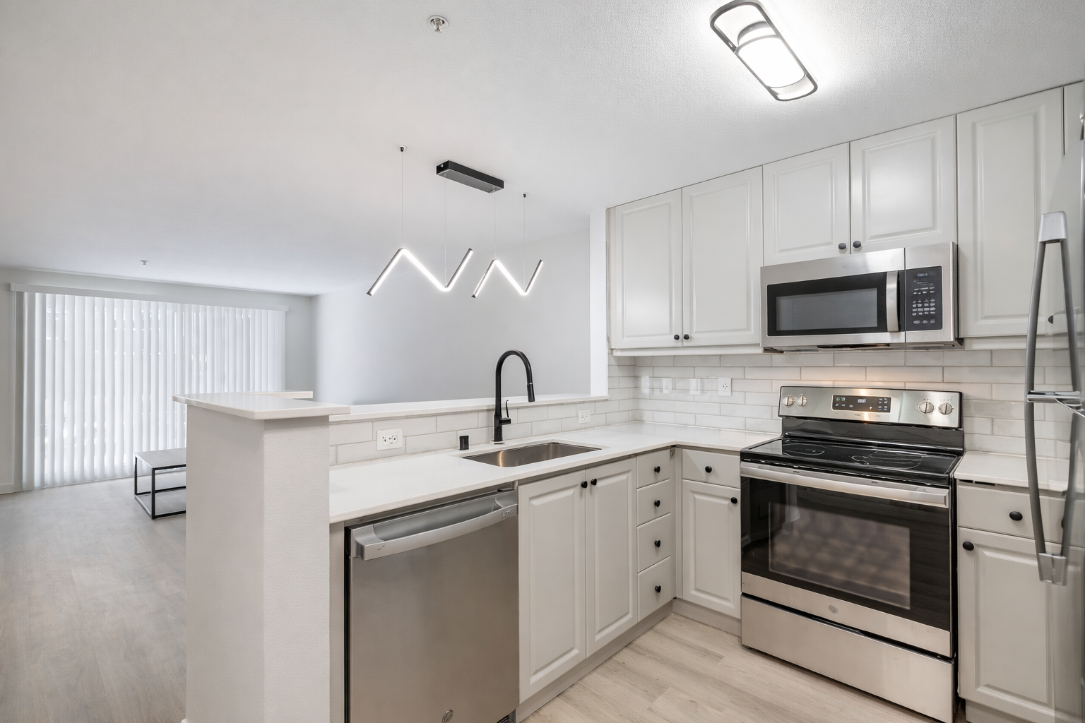 Modern kitchen at Ainsley Apartments near UW featuring white cabinets, stainless steel appliances, and subway tile backsplash.