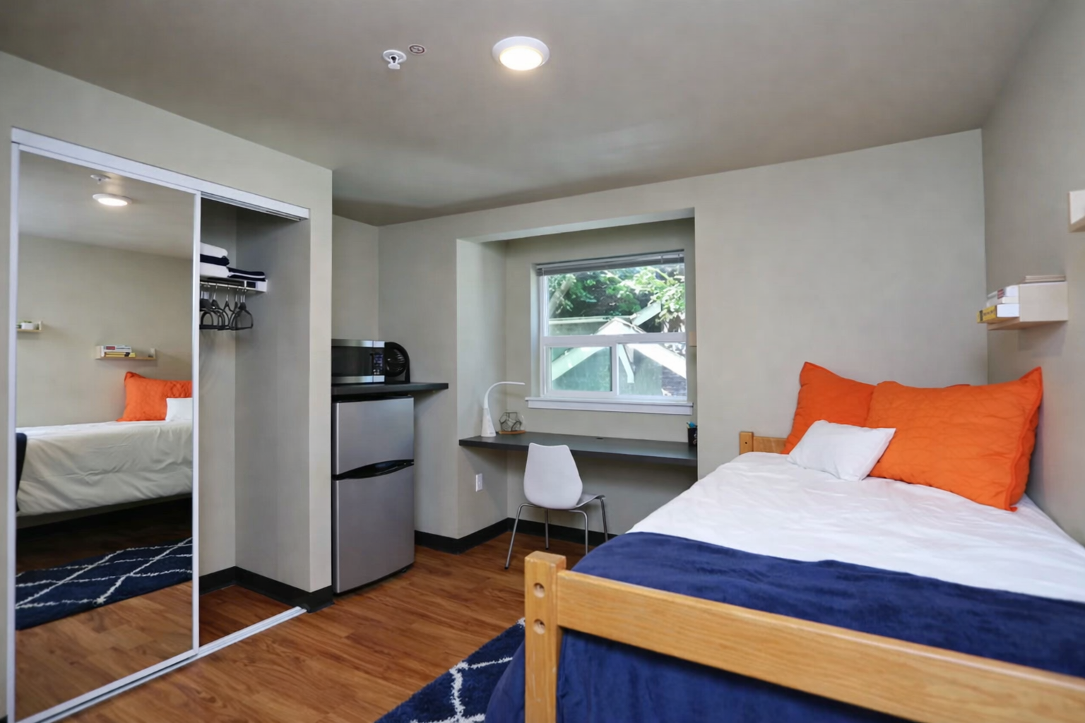 Bedroom at Ainsley Apartments in Seattle’s University District with hardwood floors and large window.