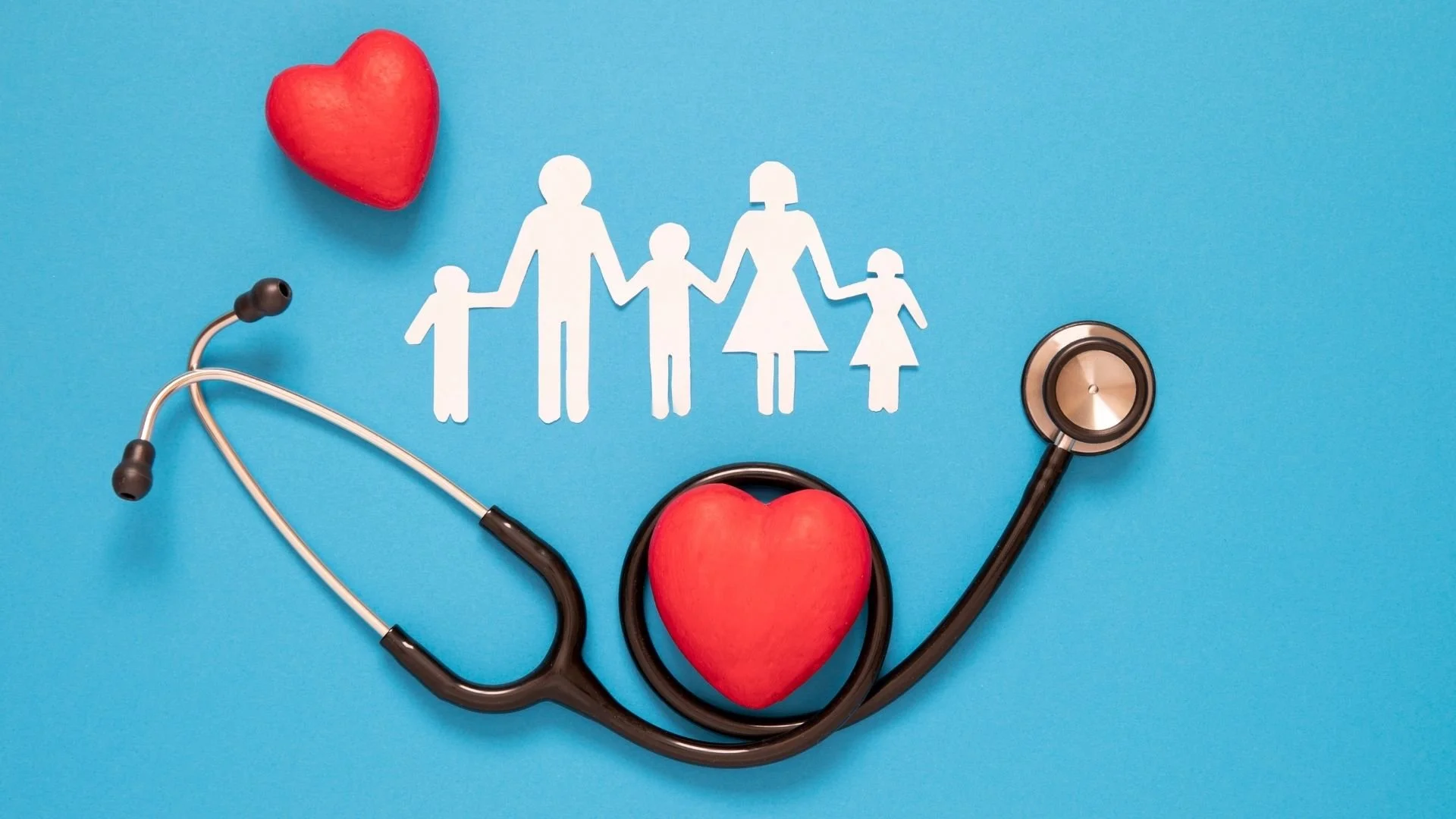 Medical stethoscope and paper cutouts of a family with two adults and two children, around a large red heart, on a blue background.