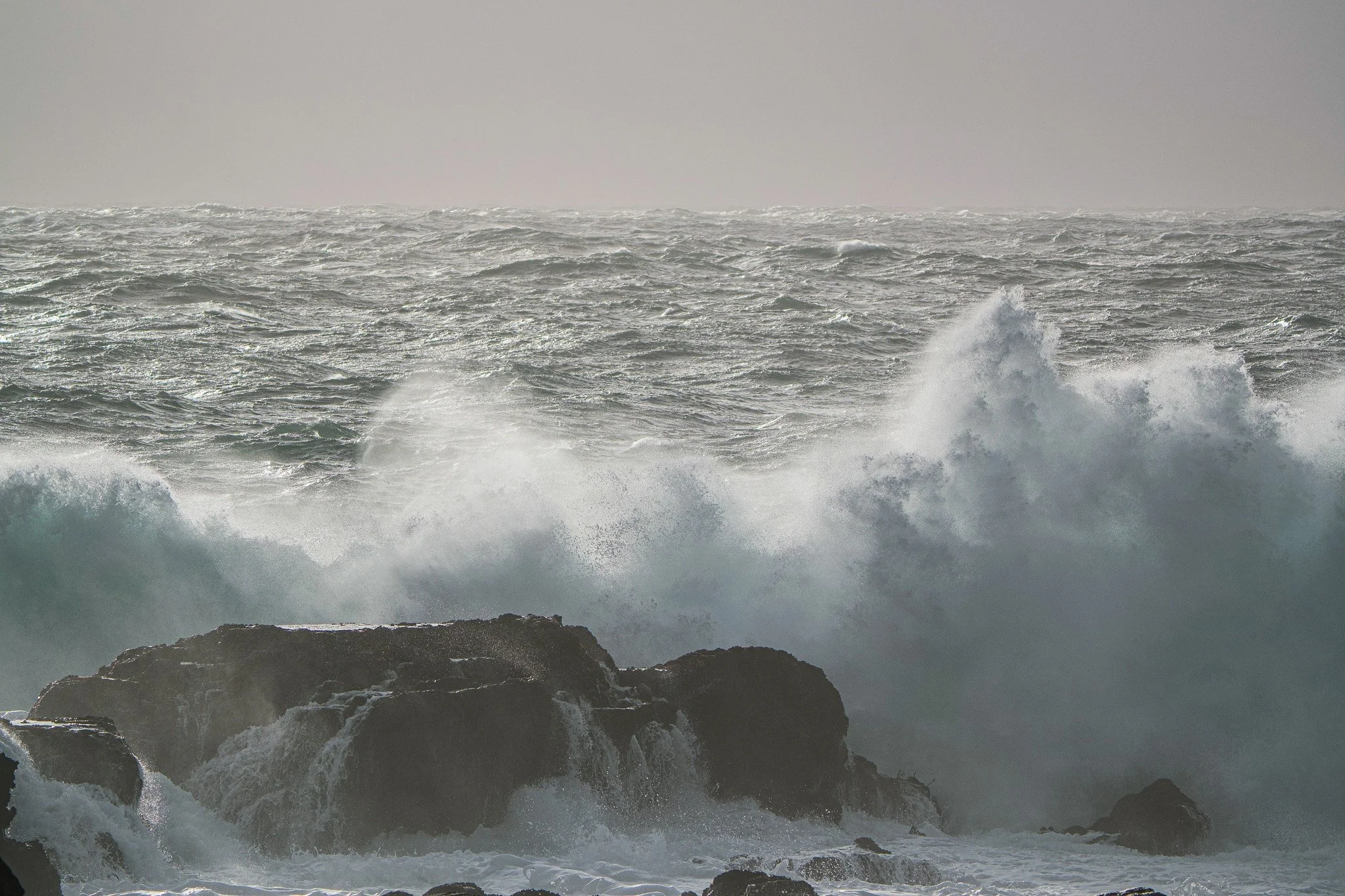 Ocean waves crashing against rocks during a storm.