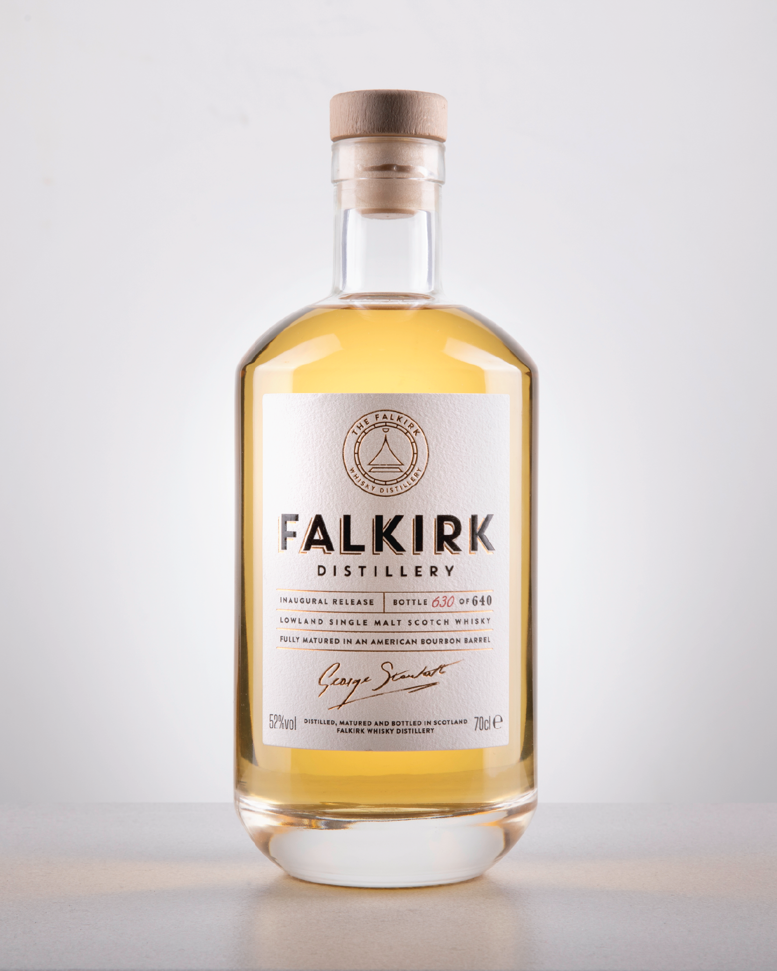 A bottle of Falkirk Distillery lowland single malt Scotch whisky with a light golden color, white label, wooden cap, and minimalist design.