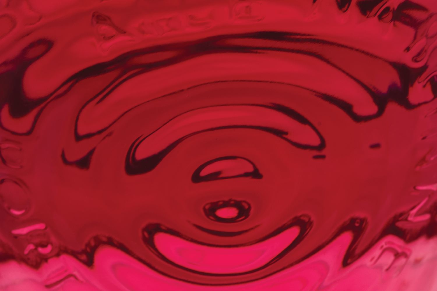 Close-up of a pink and black marbled liquid surface with swirling patterns.