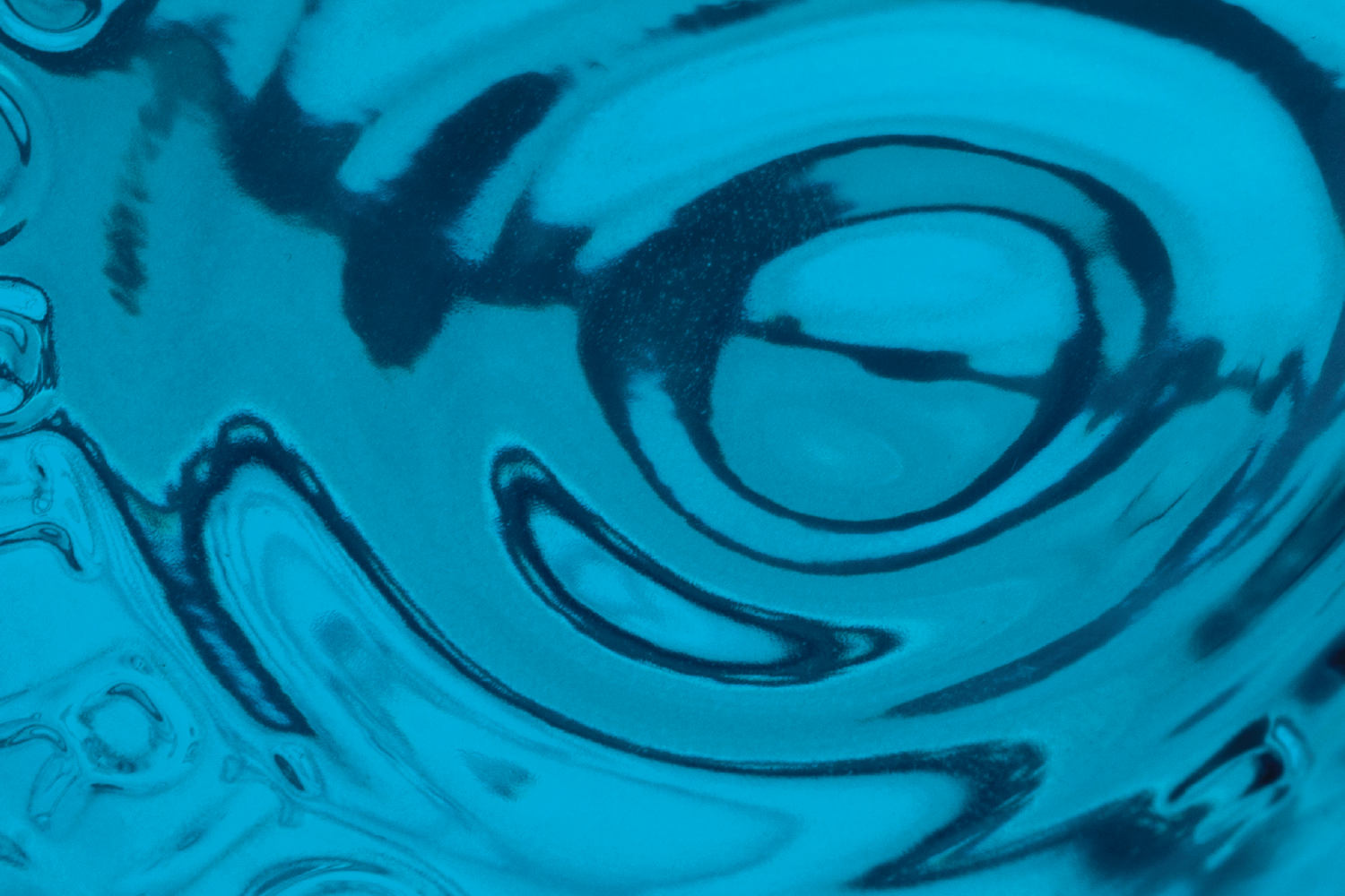A blue abstract swirl pattern in water, creating a vortex-like design.
