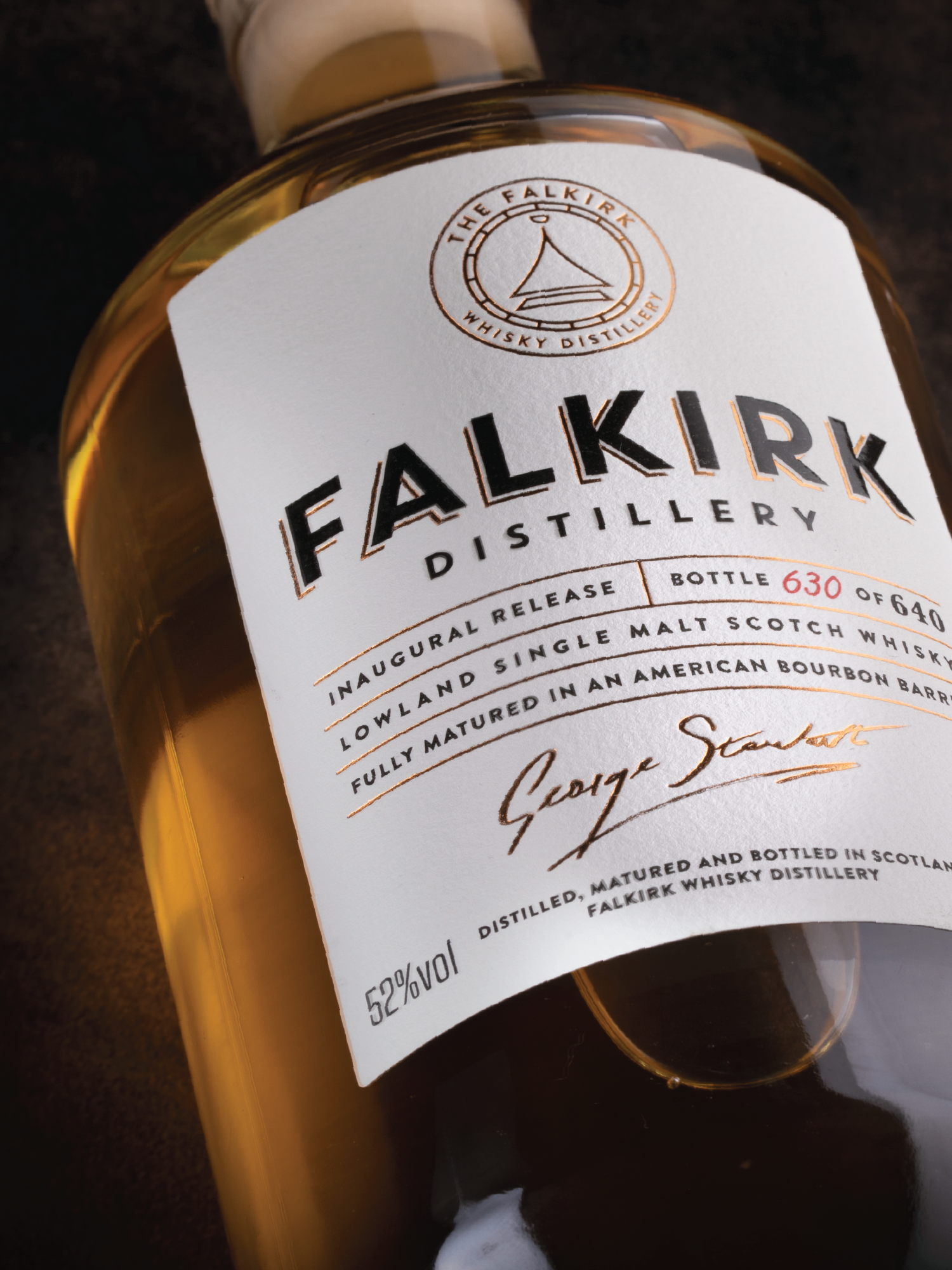 Close-up of a whisky bottle from Falkirk Distillery, featuring the label with details about the whisky's age, type, and signature of George Stuart.