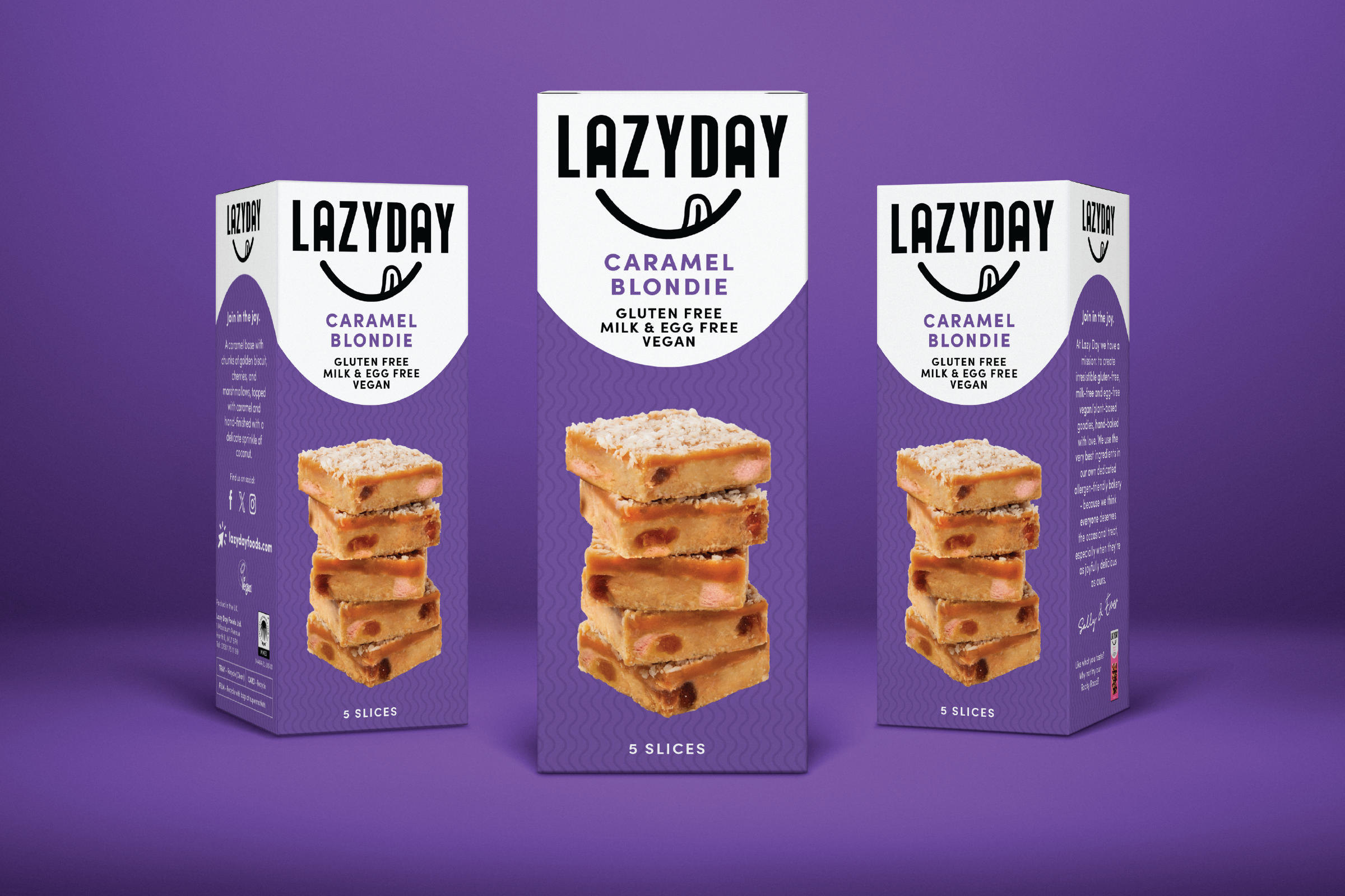 Three boxes of LazyDay Caramel Blondie vegan, gluten-free dessert slices on purple background. The boxes show images of stacked caramel blondie slices and the front label indicates flavor and dietary info.