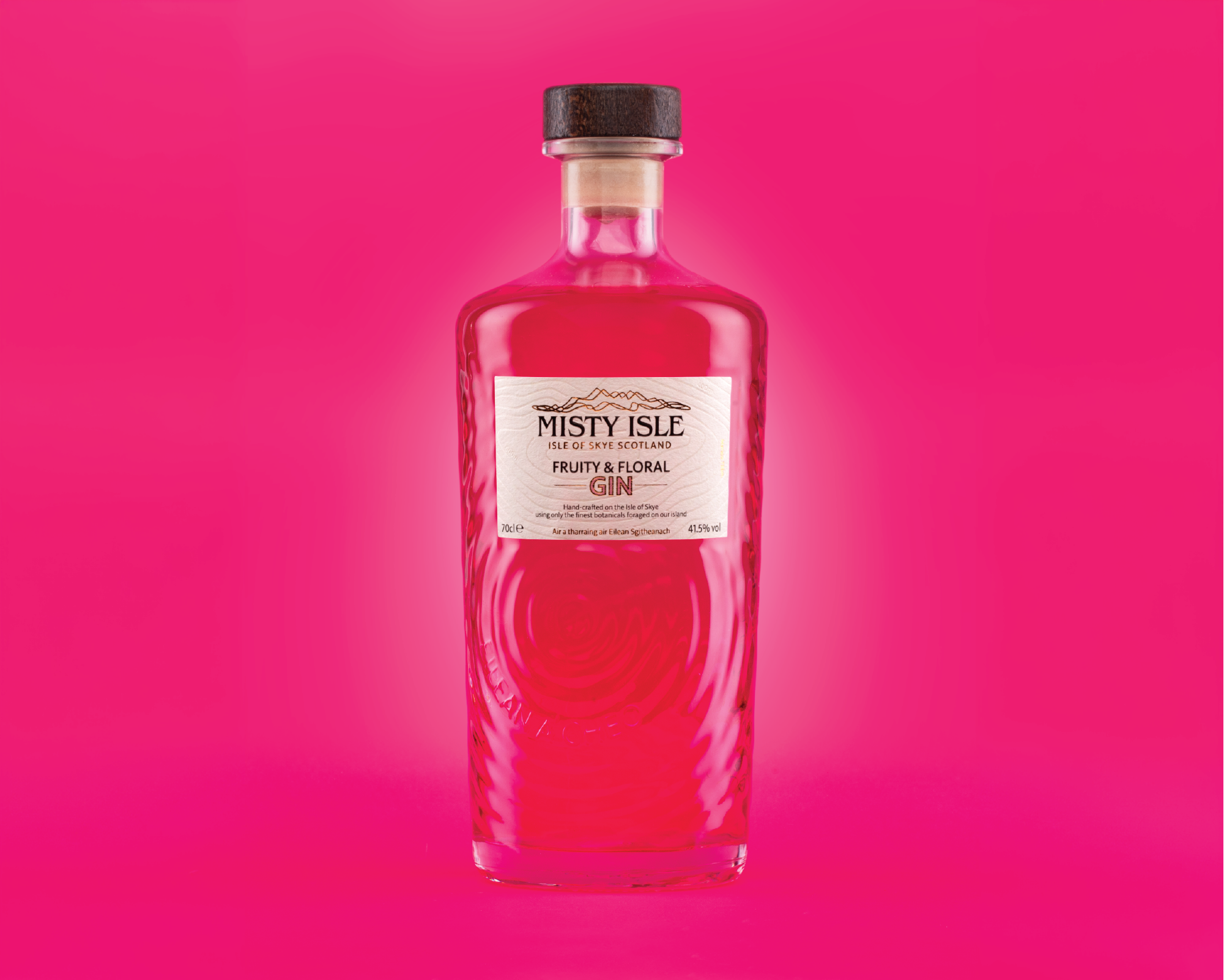 A pink bottle of Misty Isle fruity floral gin on a pink background.