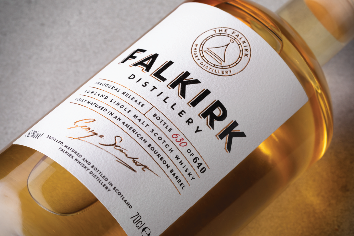 A bottle of Falkirk Distillery whisky with a white label, featuring the Falkirk Distillery logo, details about the whisky including it being a lowland single malt scotch whisky, bottled at 63.0% alcohol, with signature, and located in Scotland.