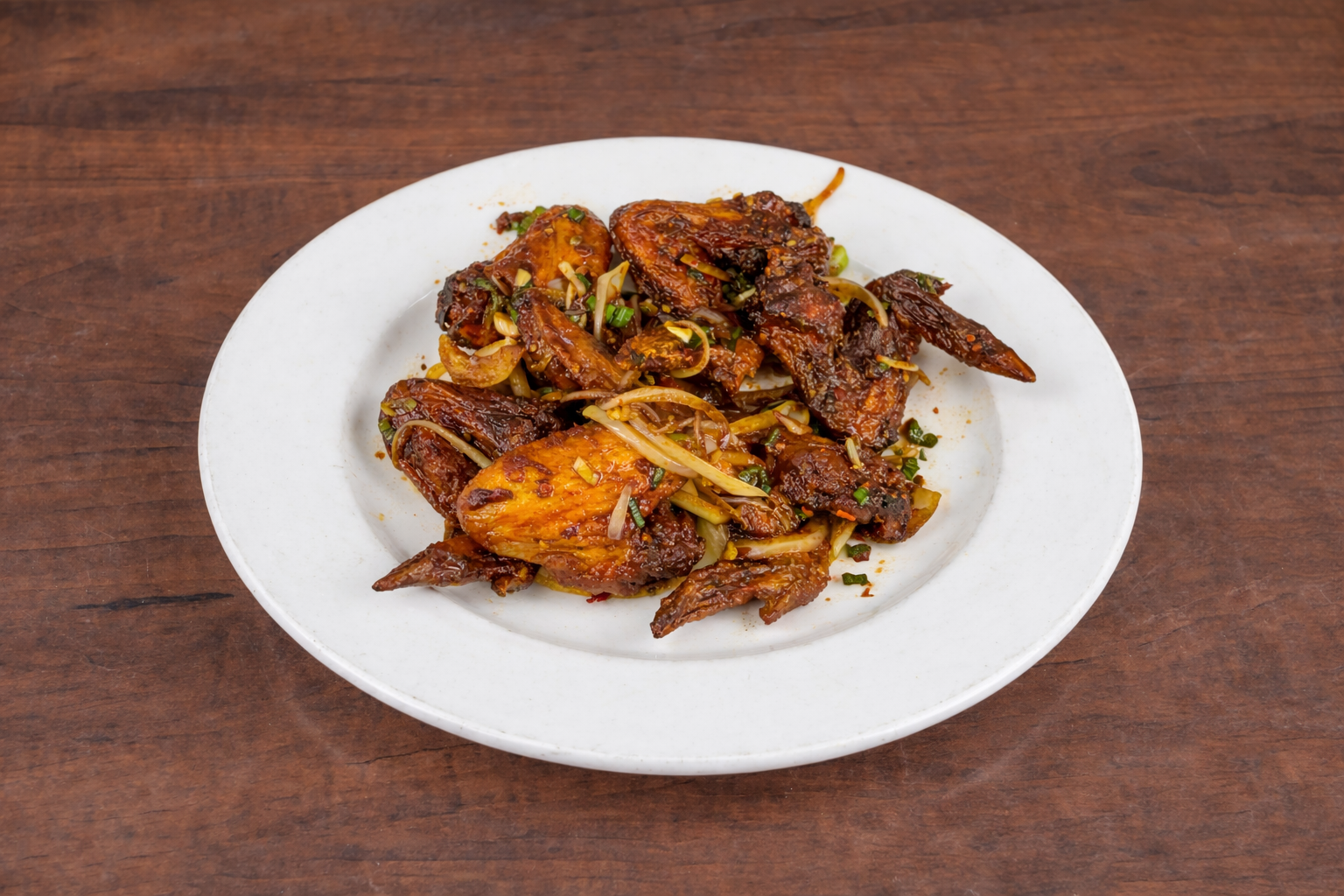 Plate of stir-fried chicken with vegetables on a wooden table.