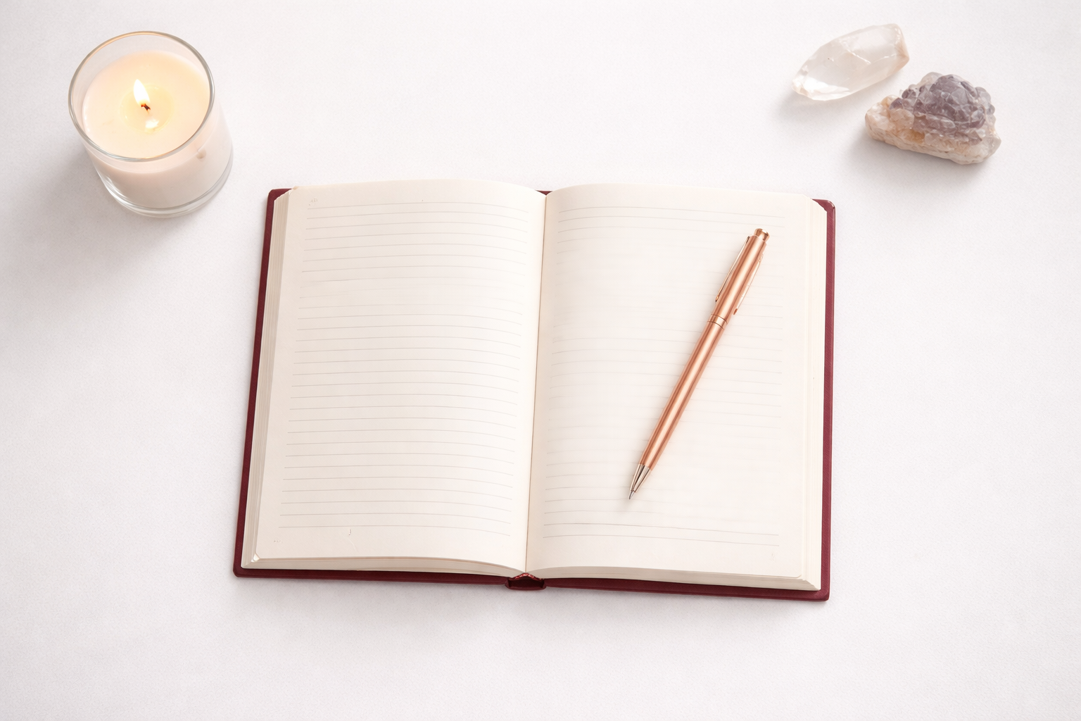 Open journal on a white desk with candle and crystals, representing reflection, emotional healing, and the alignment process.