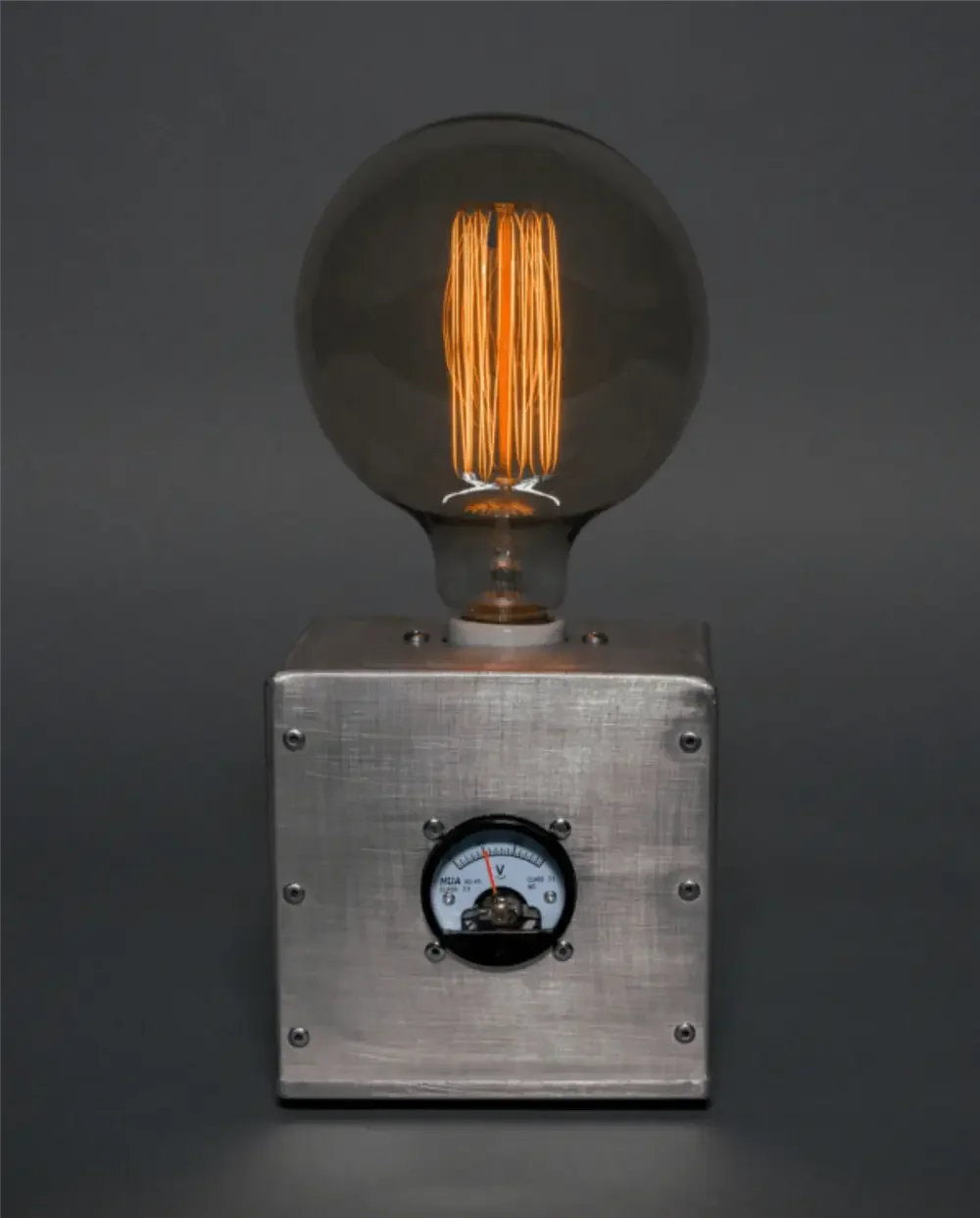 A glass light bulb with an orange filament inside, mounted on a metallic fixture with a background of dark gray.