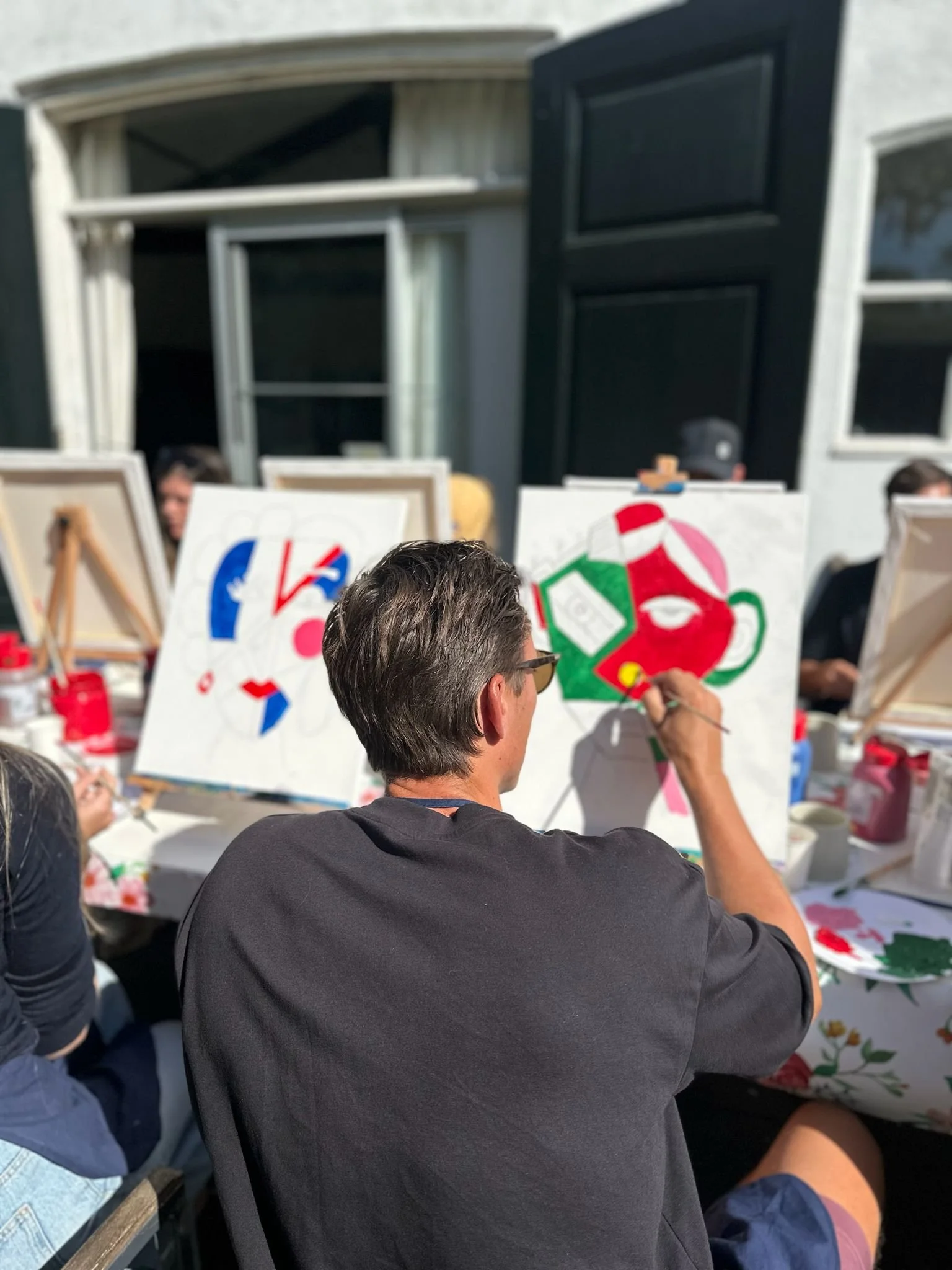 Mensen die buiten schilderijen maken tijdens een kunstworkshop.