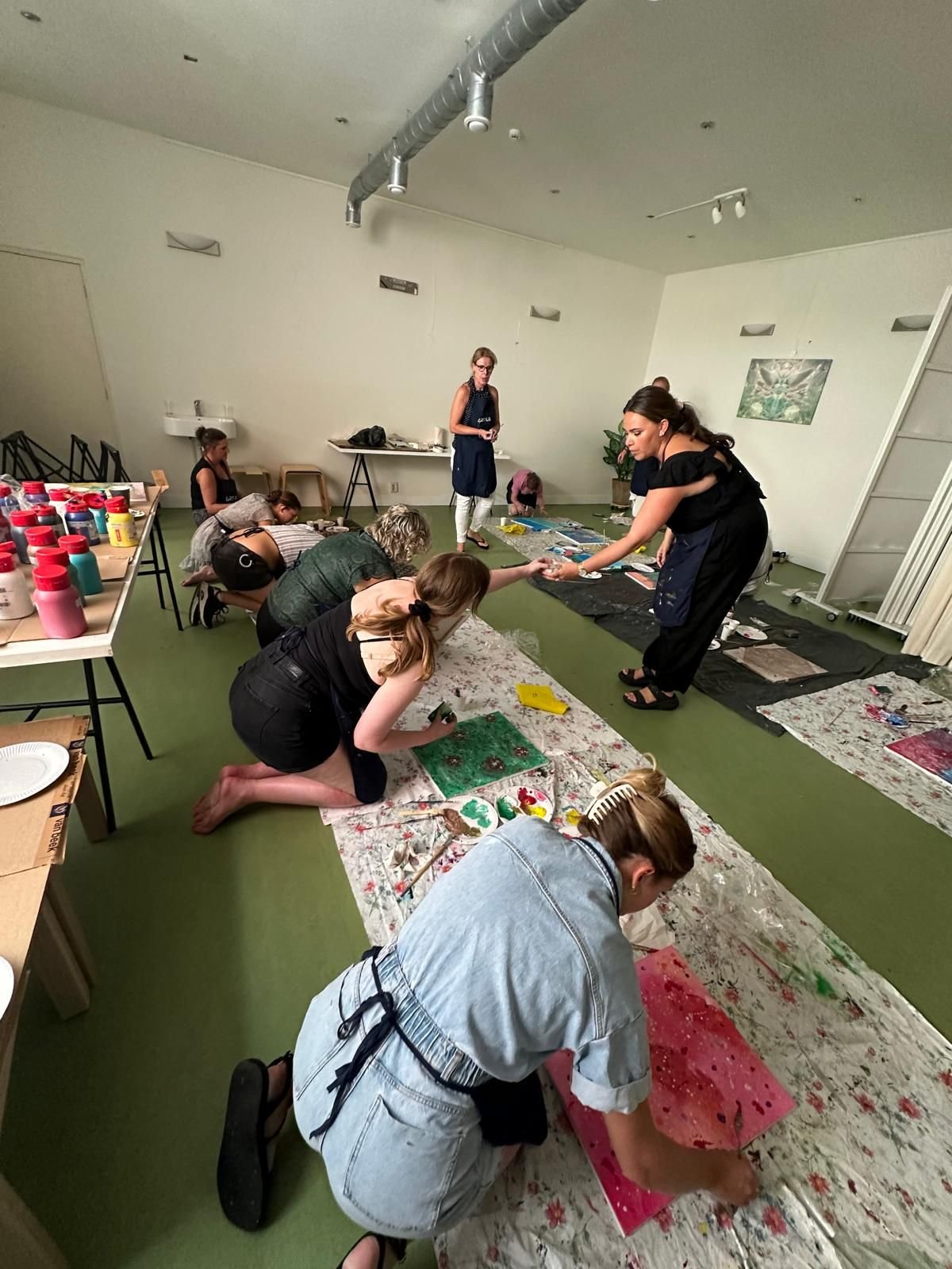 Mensen die schilderen en knutselen op de vloer in een kunstworkshop.