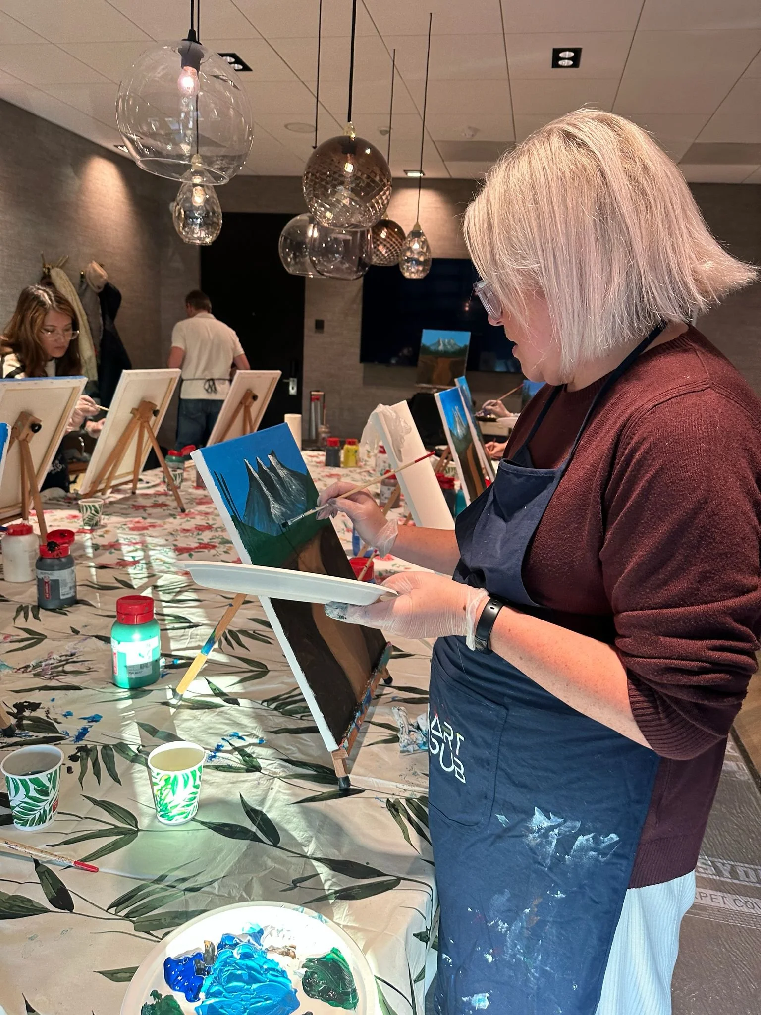 Mensen die schilderen op een kunstworkshop met verschillende schilderijen en schildermaterialen.