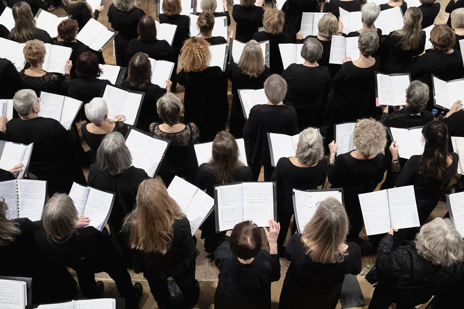 Orquesta de personas mayores tocando partituras en un concierto.