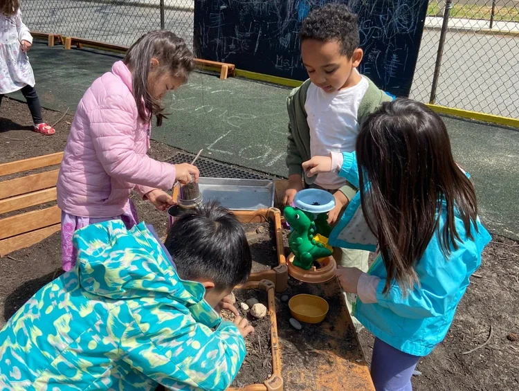 Children digging and pouring at the mud kitchen in our outdoor classroom