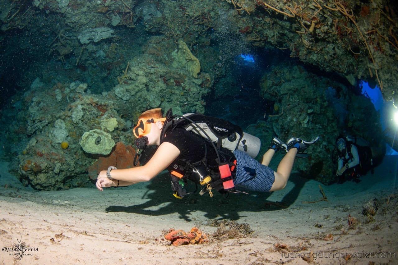 Two scuba divers explore an underwater cave with coral formations.  Cozumel Scuba Diving Dive with k8