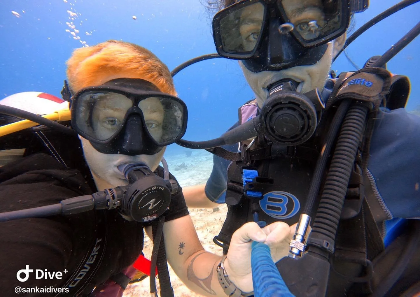 Two scuba divers underwater taking a close-up selfie, wearing masks and breathing apparatus.  Cozumel Scuba Diving Dive with k8
