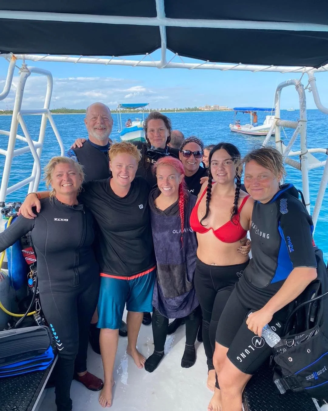 Group of people smiling on a boat with blue water and other boats in the background.  Cozumel Scuba Diving Dive with k8