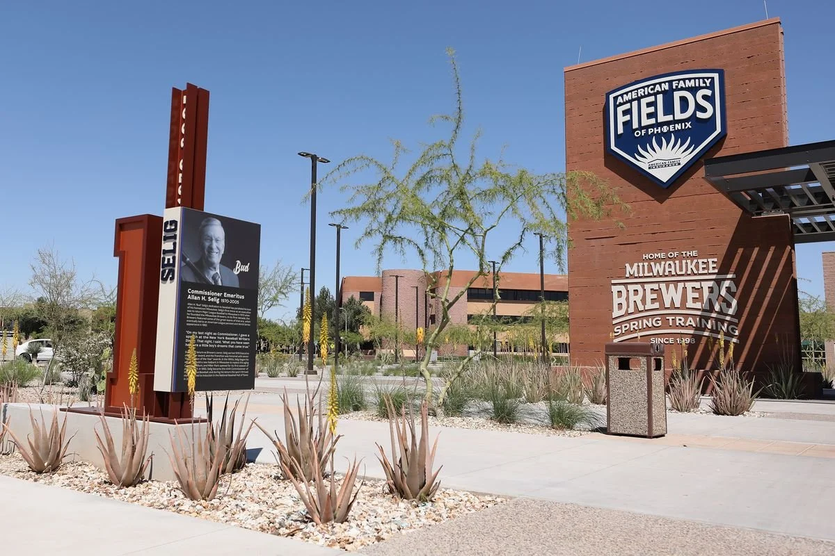 Sign for the American Family Fields of Phoenix, home of the Milwaukee Brewers spring training baseball team, with desert plants and a building in the background.