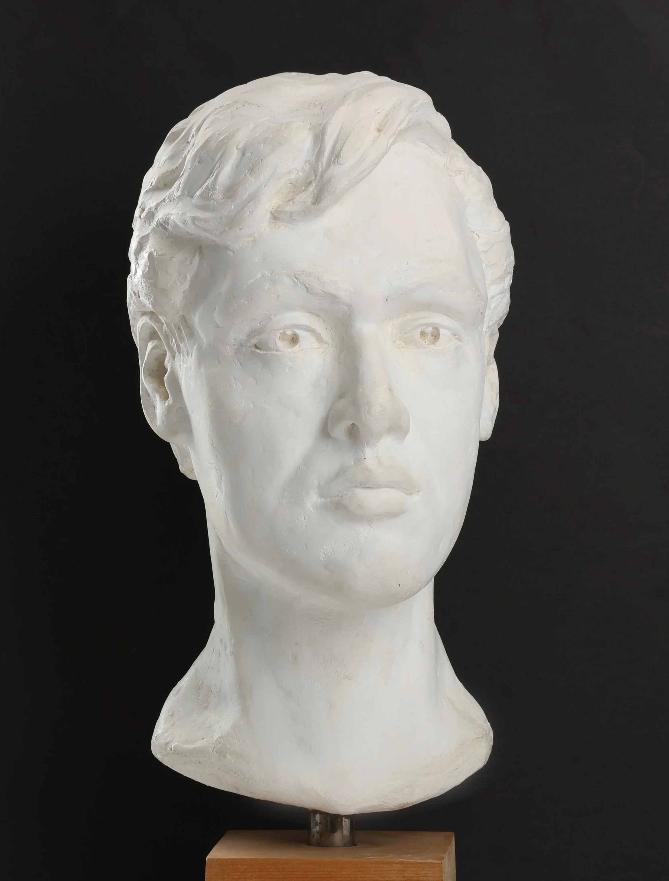 White plaster bust sculpture of a woman with short hair, set against a black background.