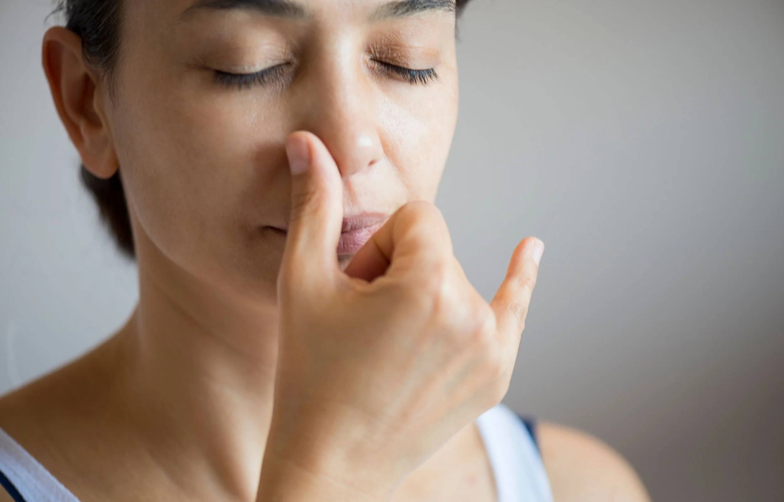 A woman with short dark hair has her eyes closed and is practicing pranayama