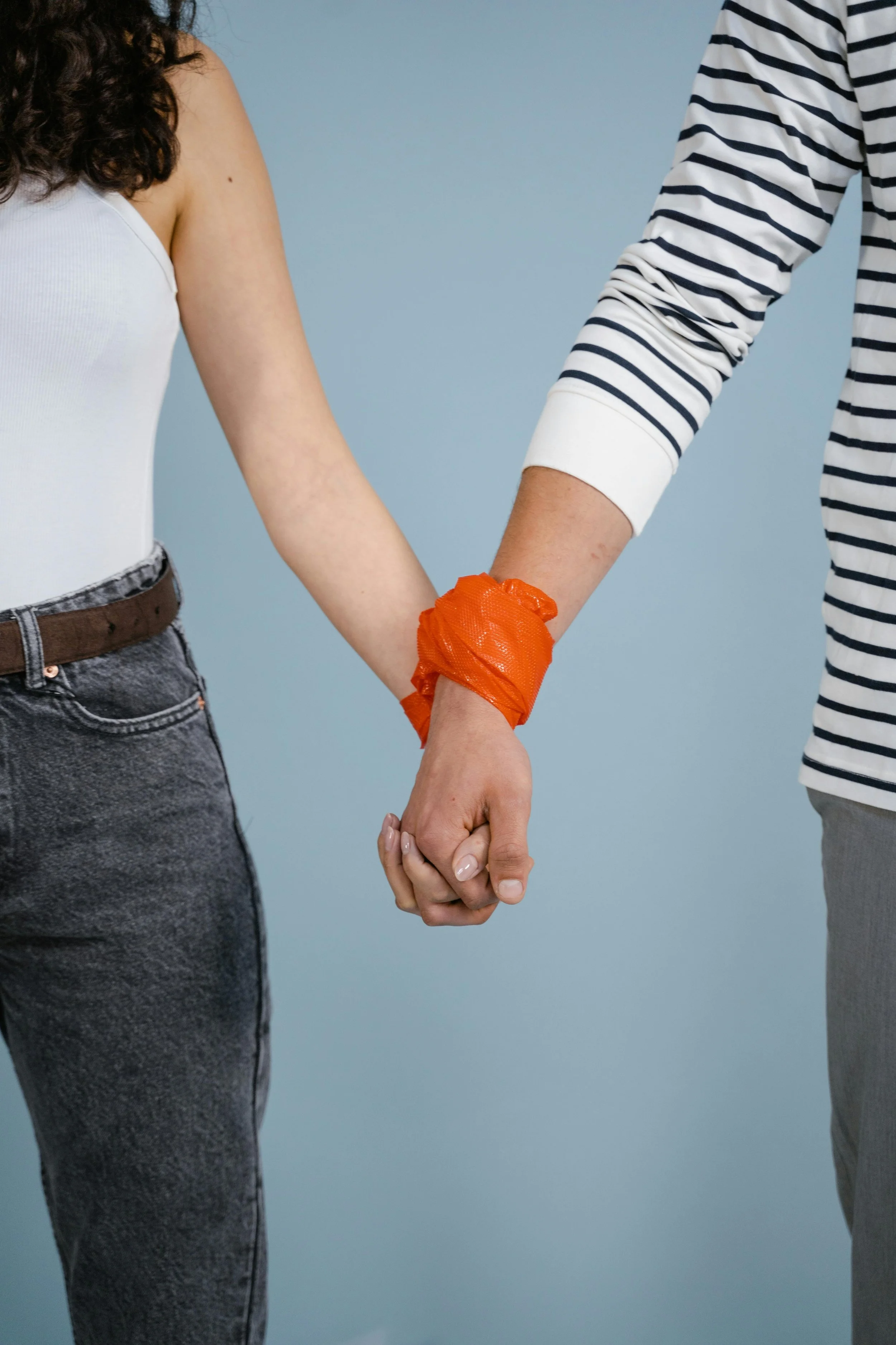 Couple standing together with their hands tied by rope.