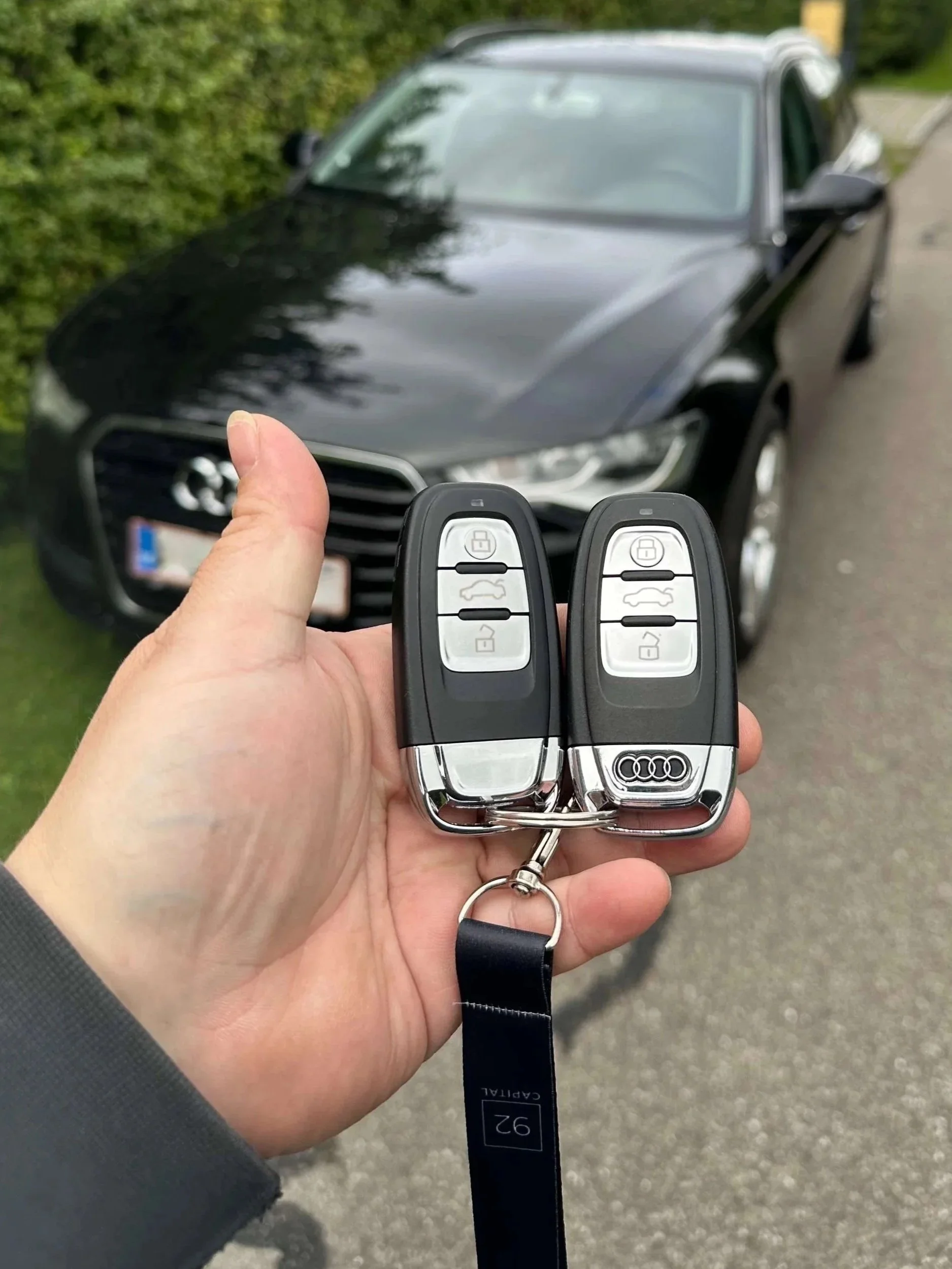 Ny Audi bilnøgle kodet og klar til brug foran sort Audi