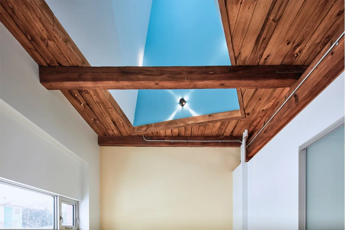 vaulted wood ceiling with exposed beams and a central skylight/light well