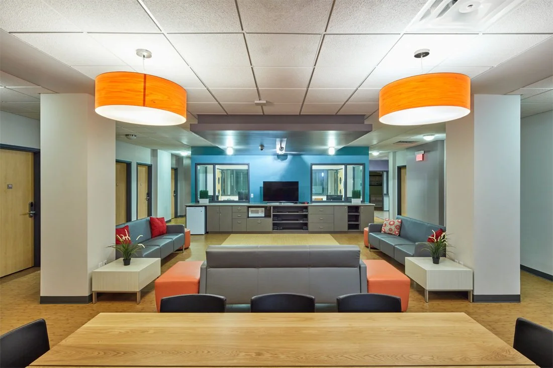 Interior of a modern lounge or common room with couches, coffee tables, and a television.