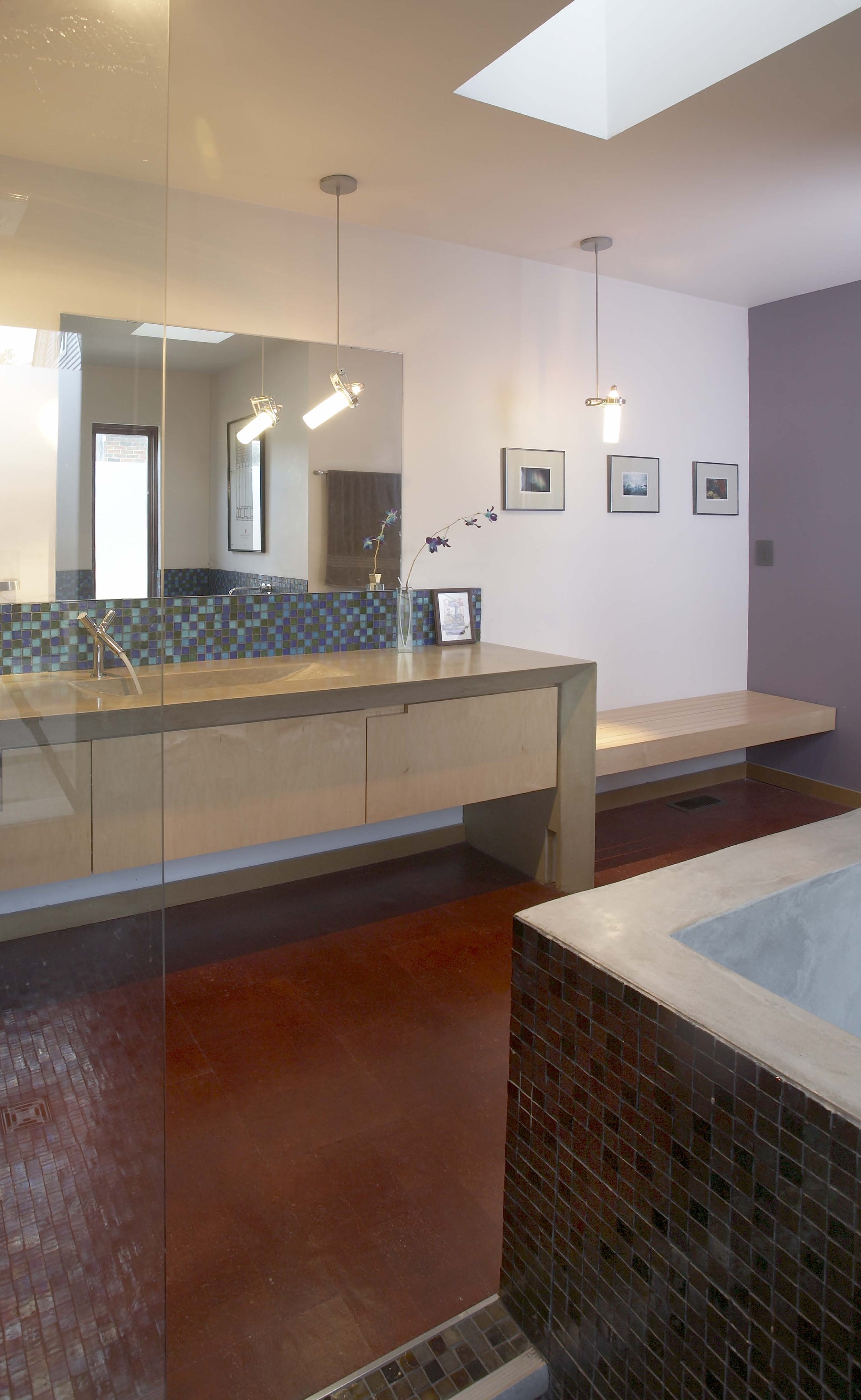Bathroom with a long countertop sink, blue mosaic tile backsplash, and pendant lighting.