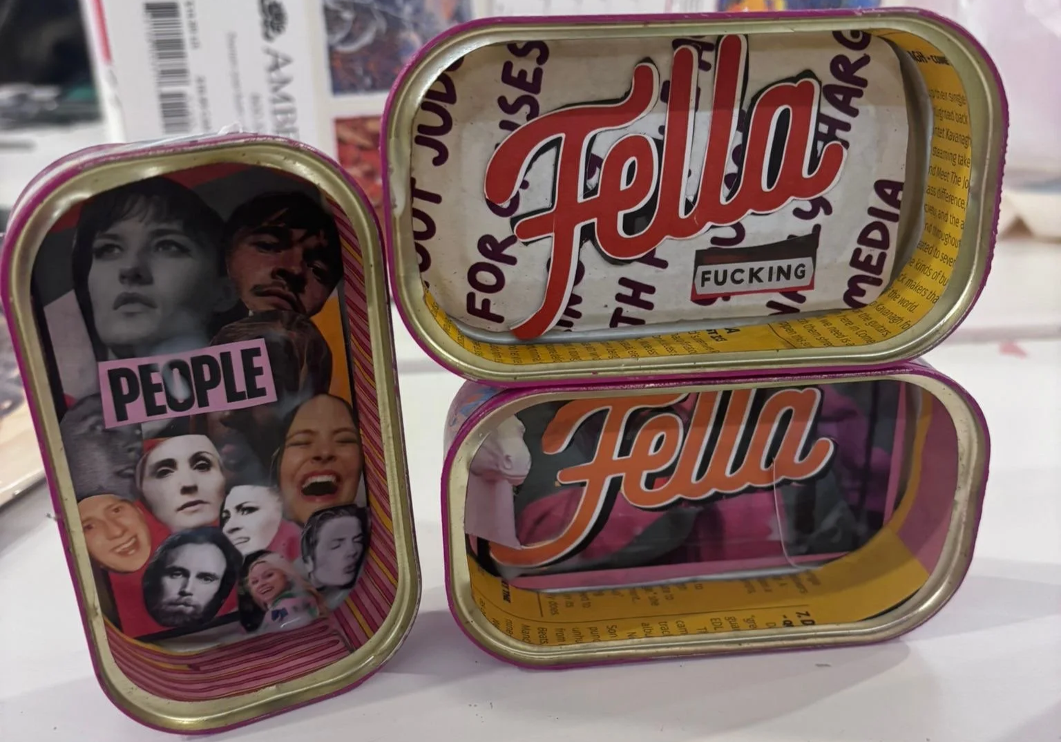 Three cans, two with the brand name Hello in stylized script, one with the word People and a collage of magazine photos of various celebrities on the front.